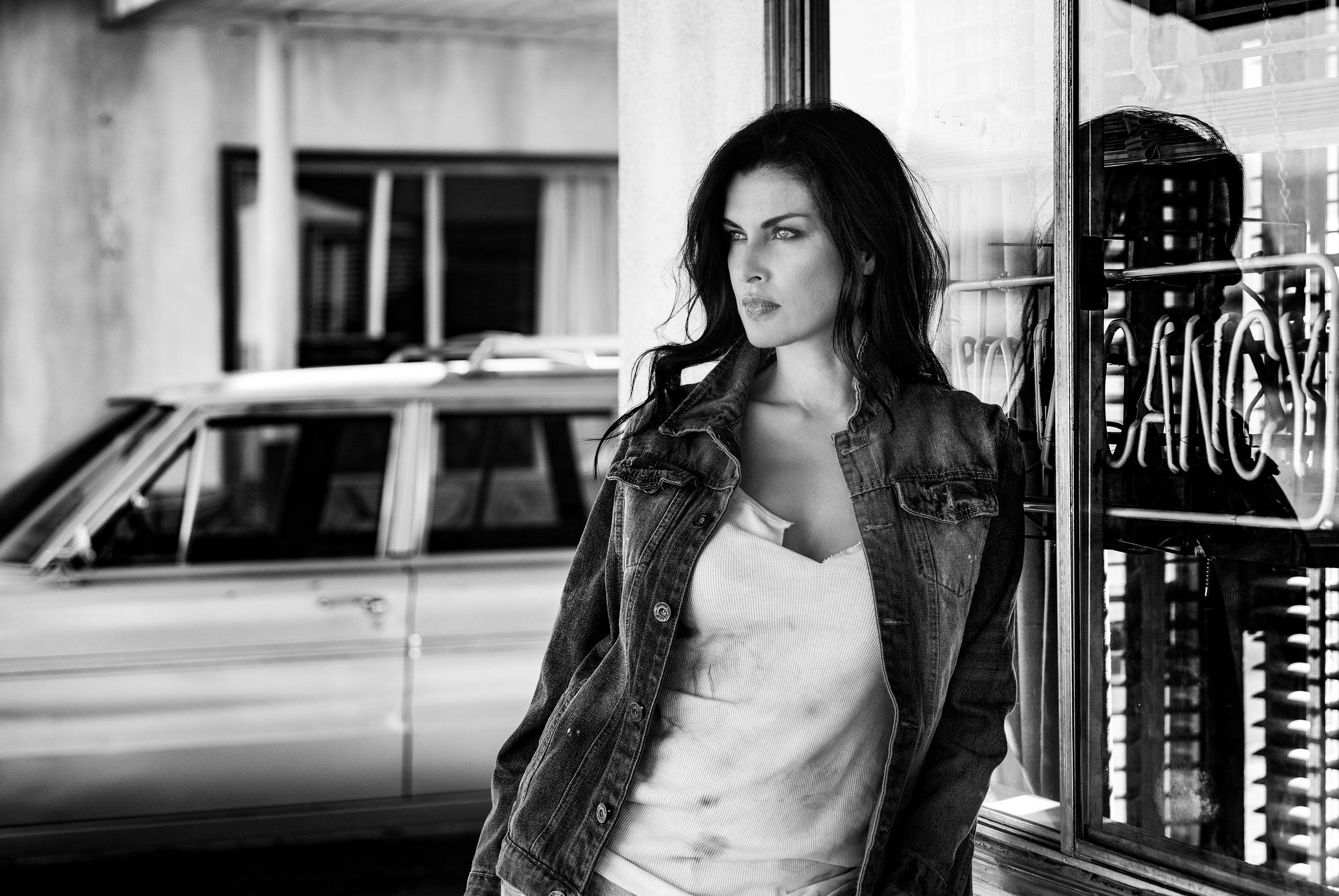 Woman in denim jacket standing by a window HD Wallpaper