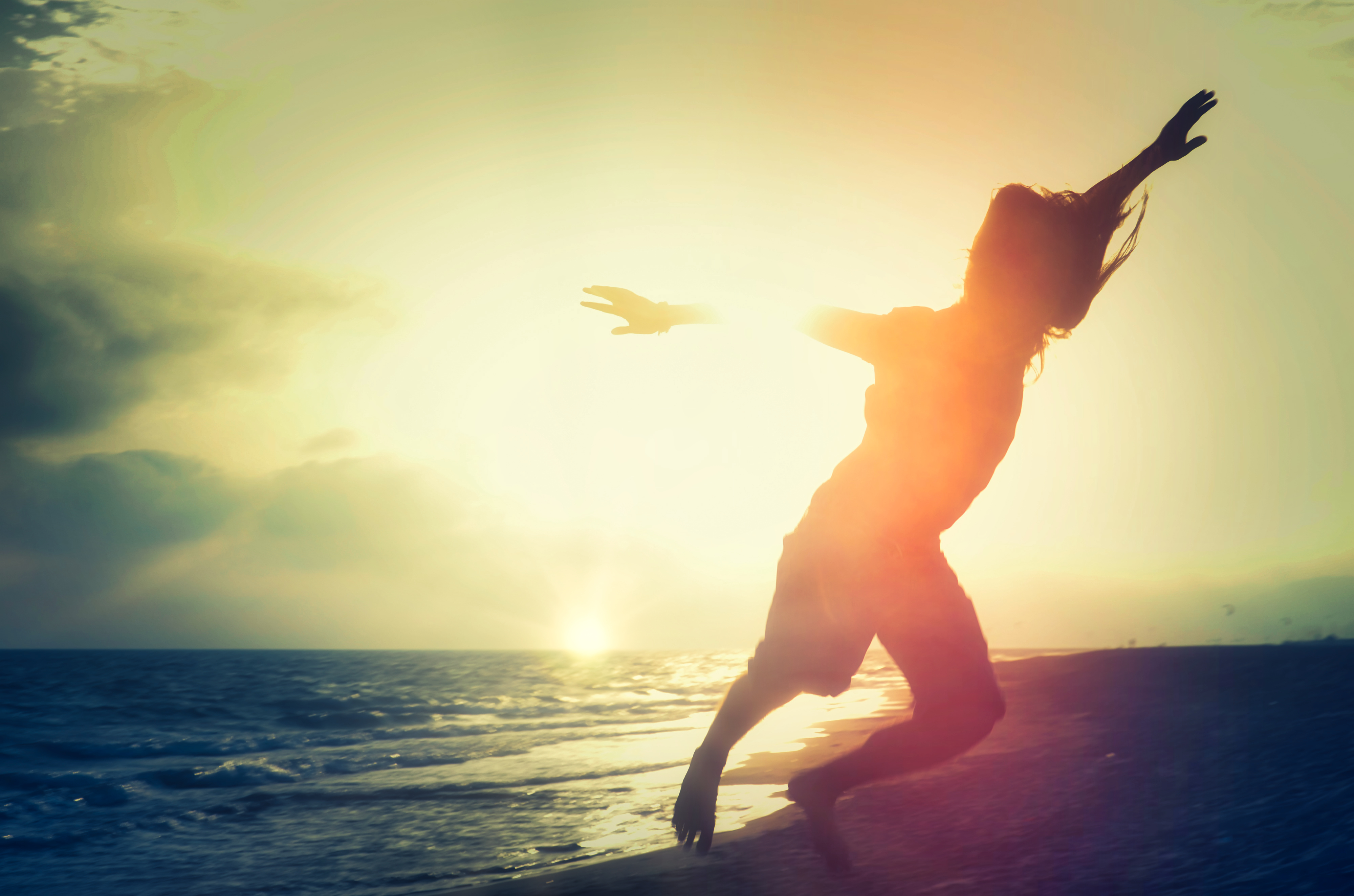 Person jumping on a beach at sunset HD Wallpaper
