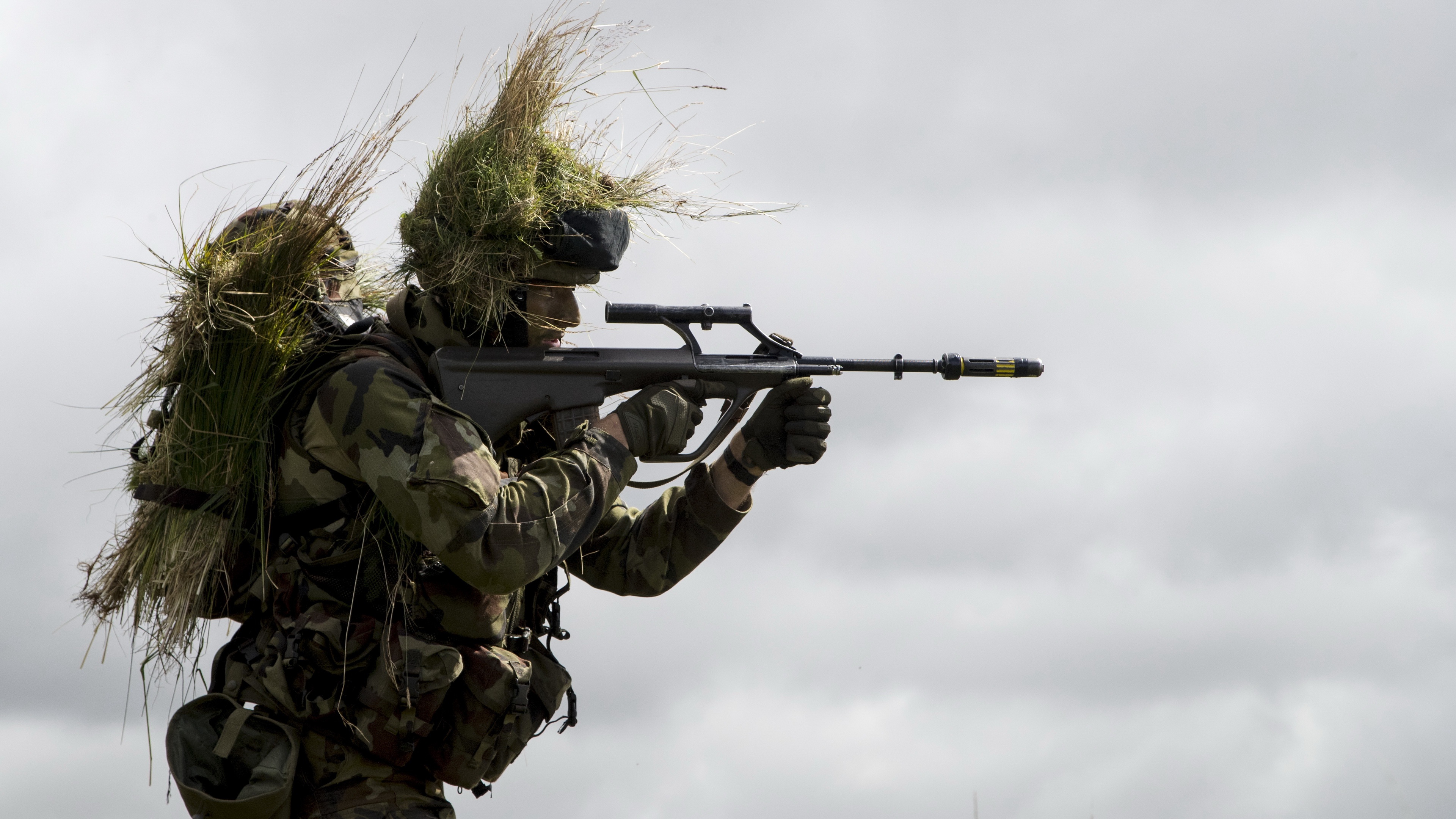 Soldier with camouflage and foliage aiming a rifle HD Wallpaper