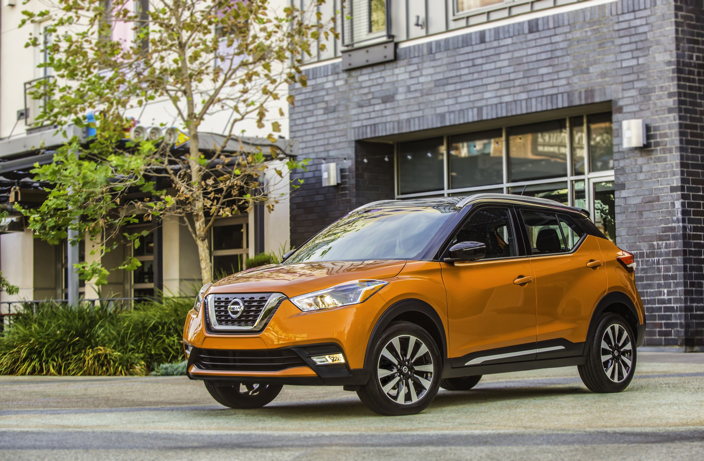 Orange Nissan Kicks SUV parked outside building HD Wallpaper