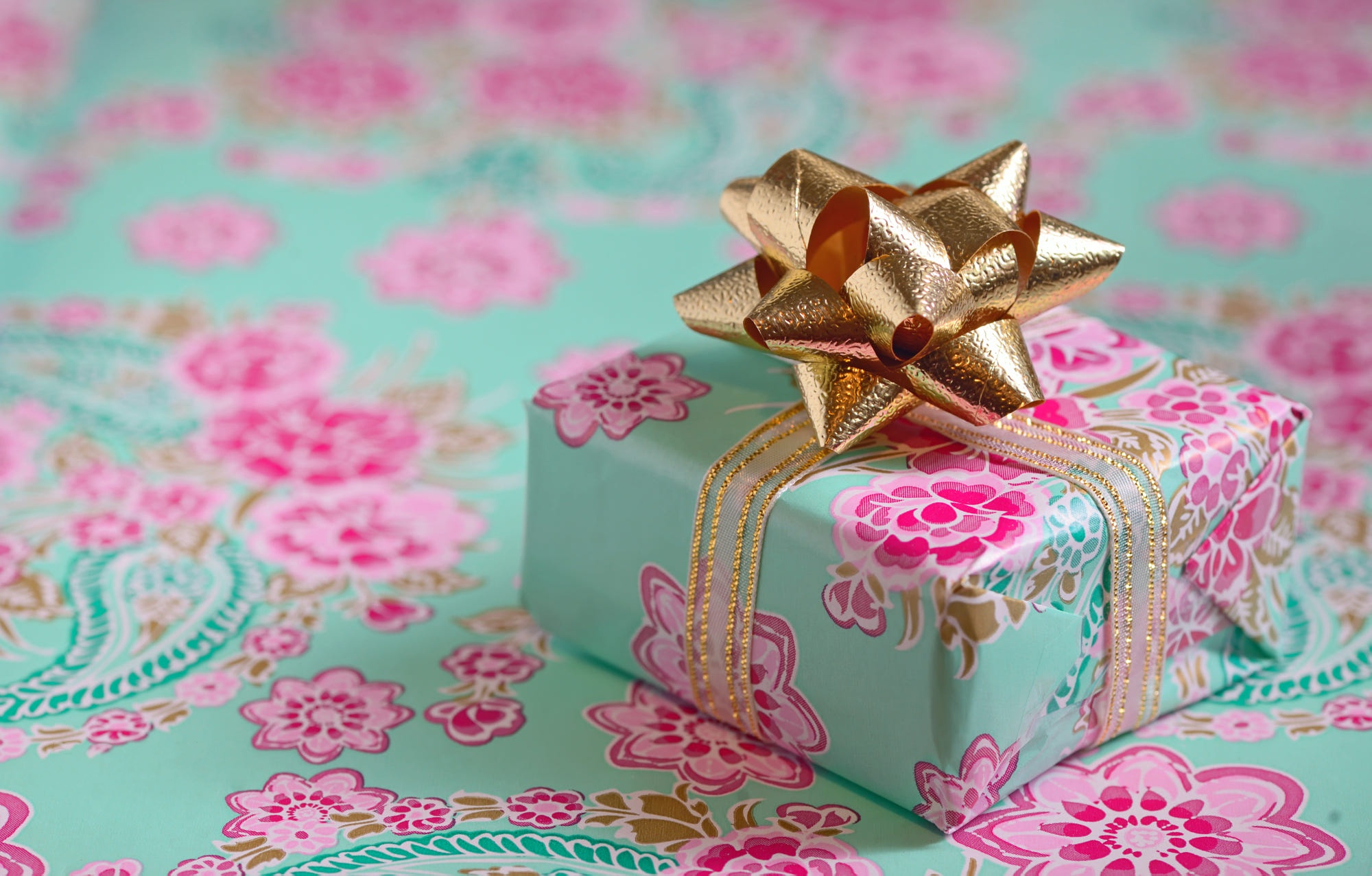 Gift box with floral wrapping and gold bow HD Wallpaper