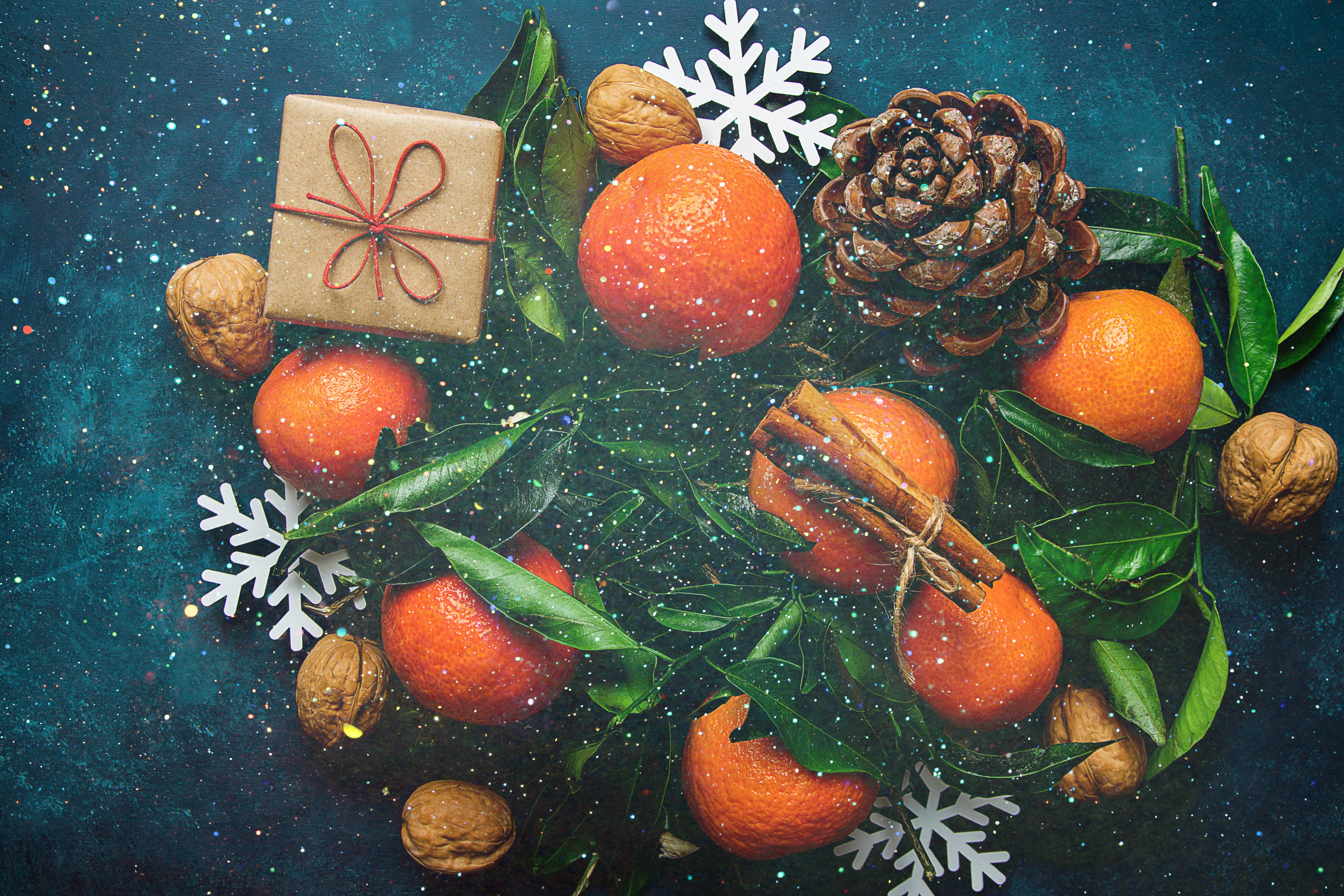 Christmas still life with mandarins, walnuts, pine cone, cinnamon sticks, gift, and snowflakes HD Wallpaper