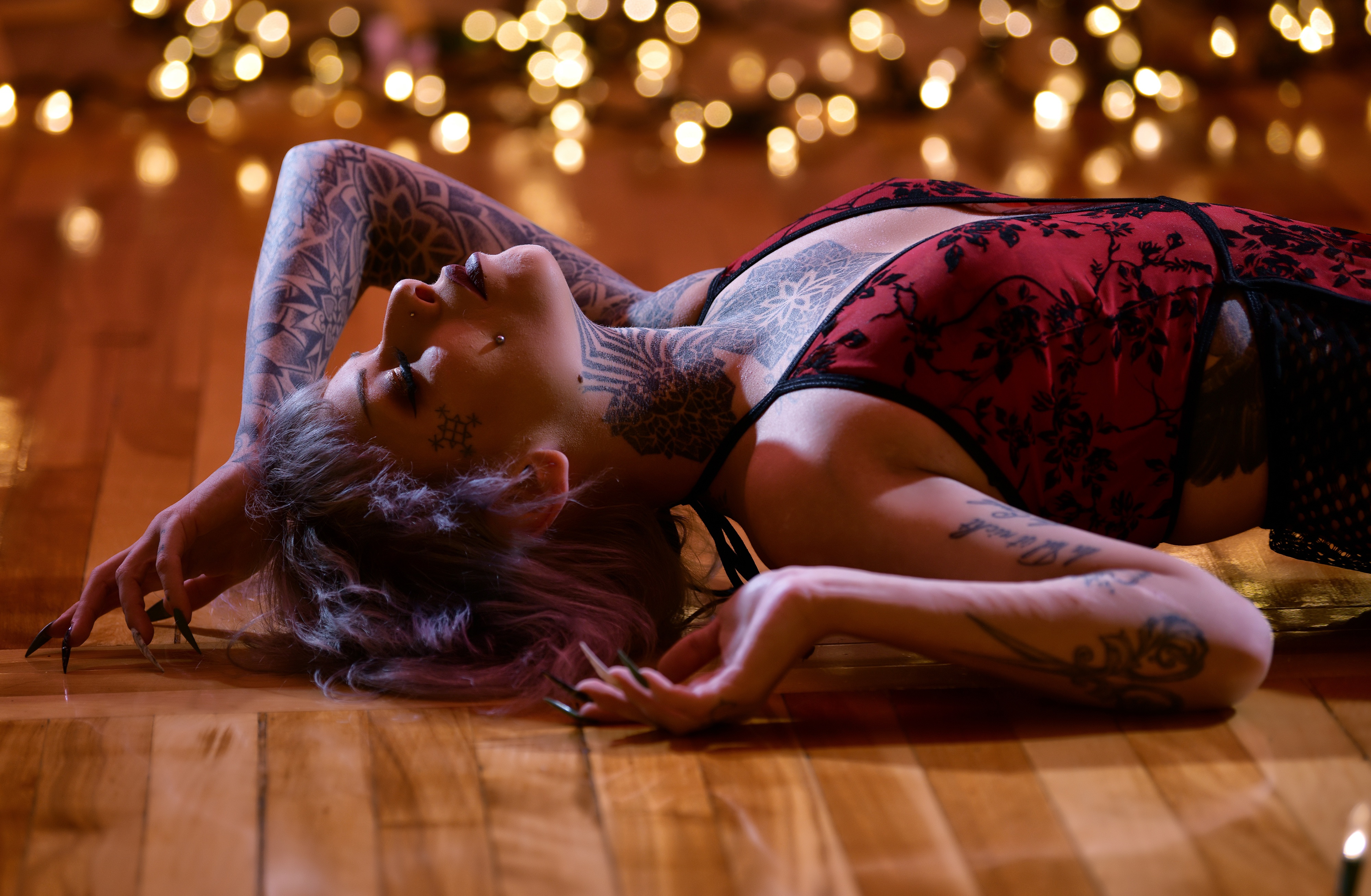 Tattooed woman lying on floor with bokeh lights HD Wallpaper