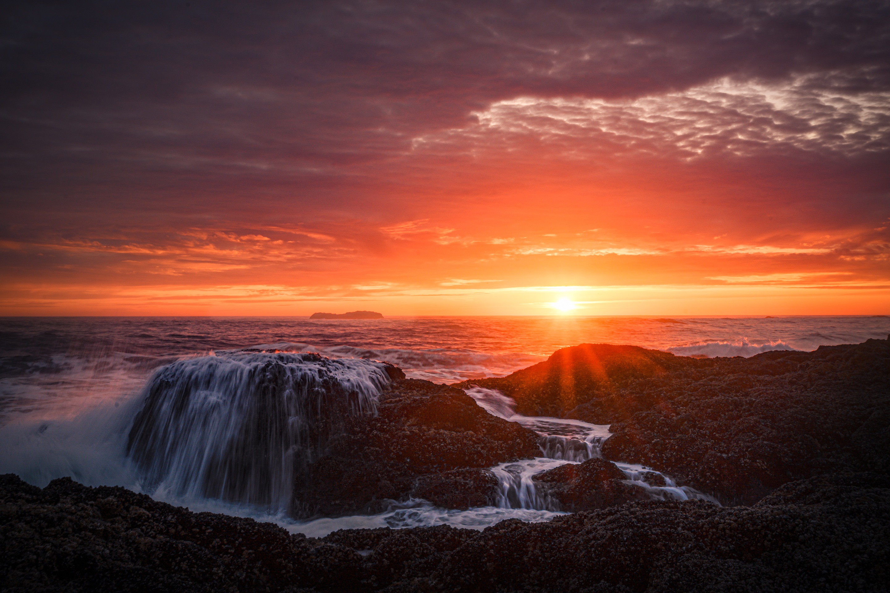Sunset over ocean with waterfall on rocks HD Wallpaper