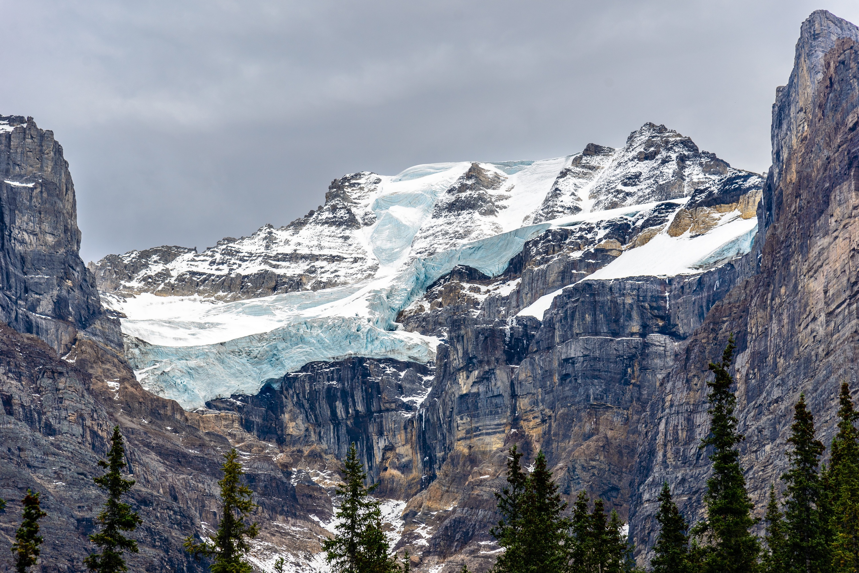 Glacier on a rocky mountain under a cloudy sky HD Wallpaper