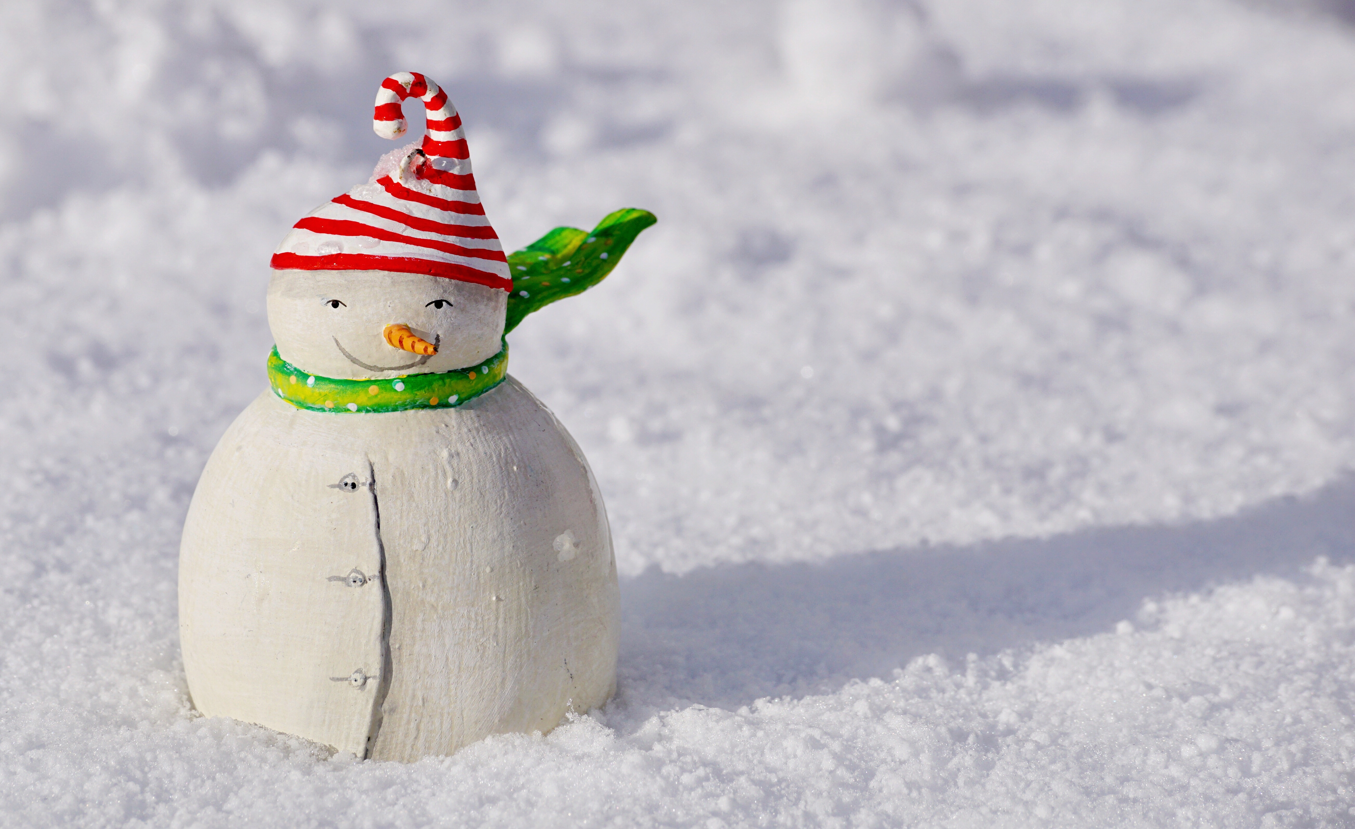Snowman figurine with striped hat and scarf in snow HD Wallpaper