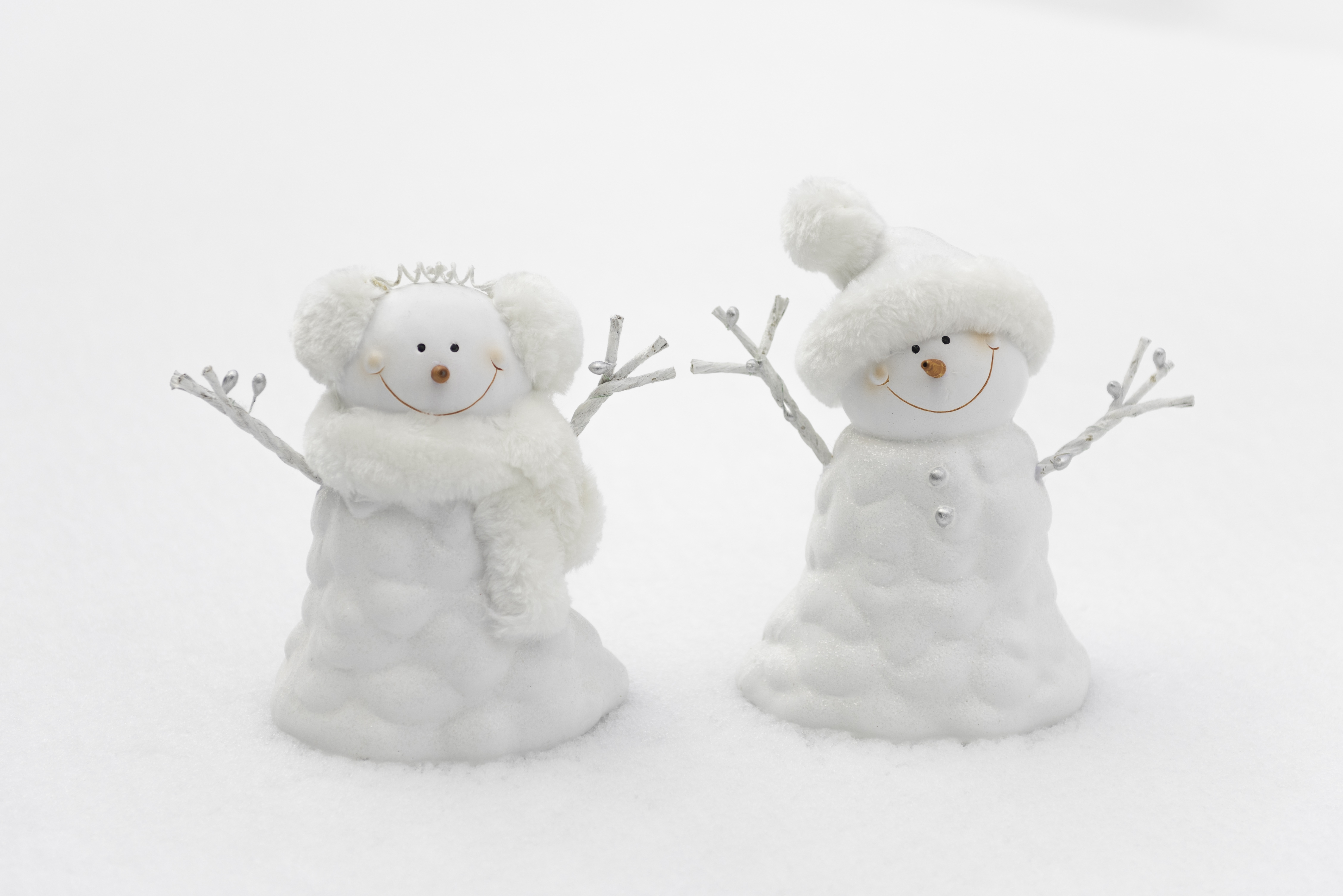 Two snowmen figurines in snow HD Wallpaper
