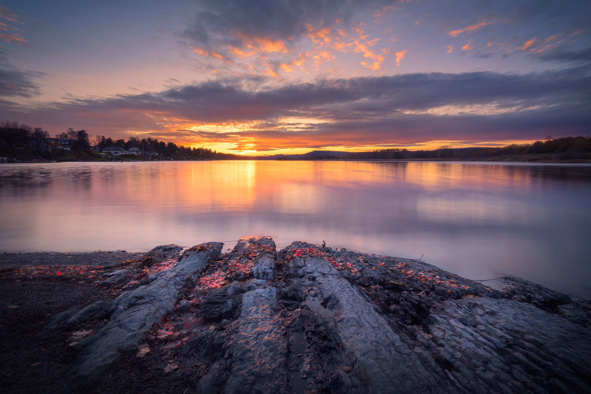 Sunset over a calm lake with rocky shore HD Wallpaper