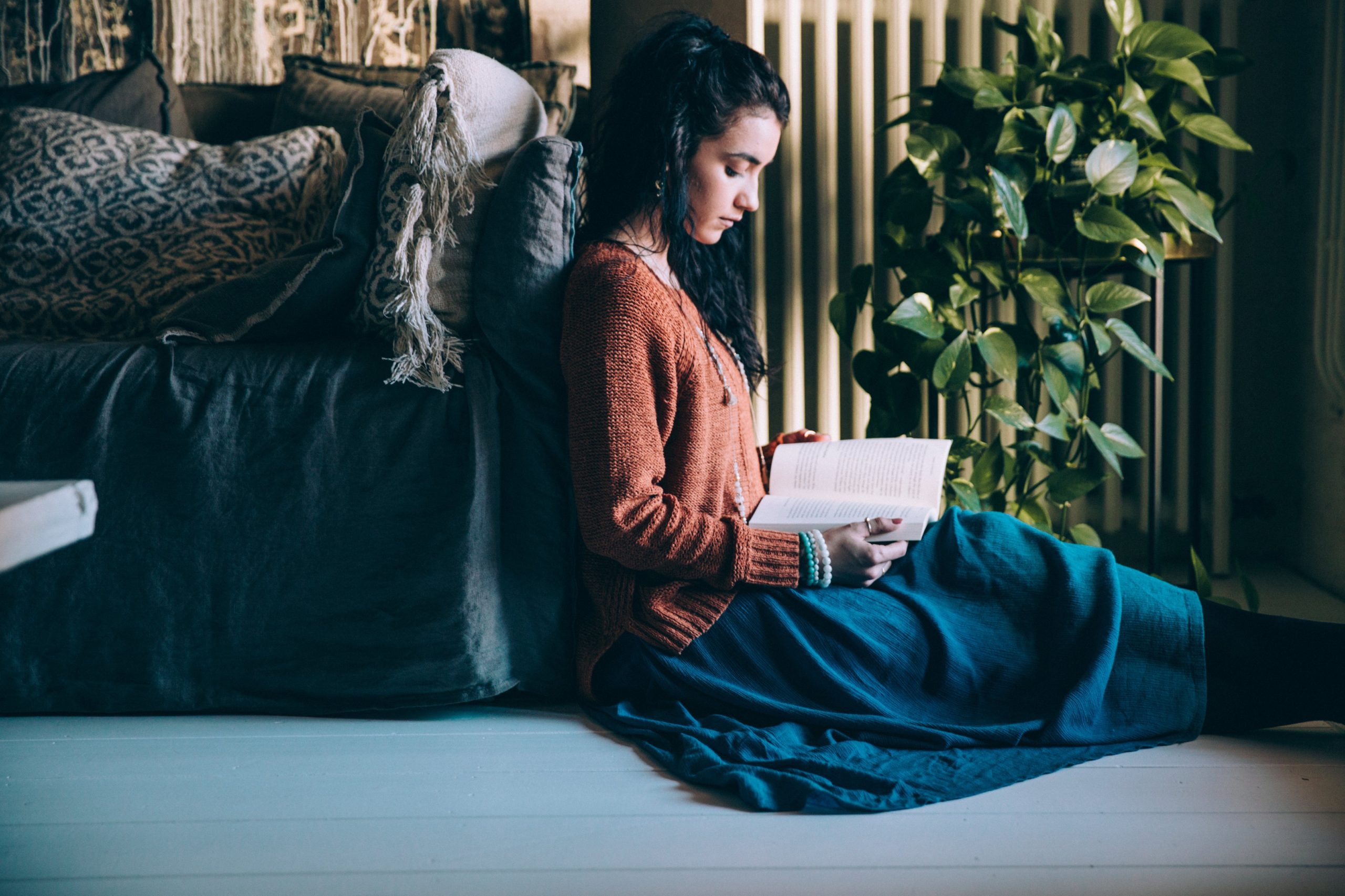 Woman reading a book on the floor by a sofa HD Wallpaper