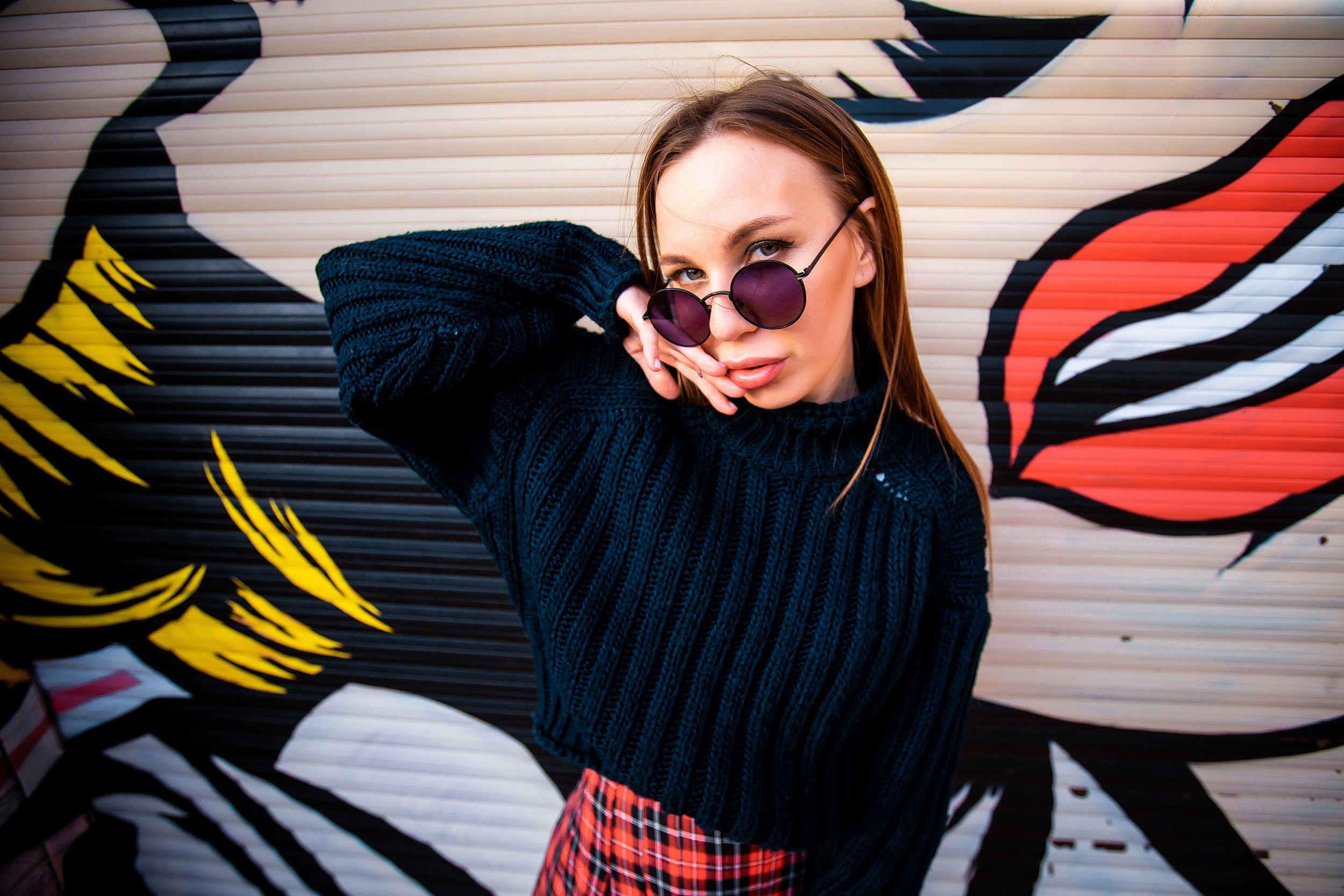 Woman in sweater and glasses in front of graffiti HD Wallpaper