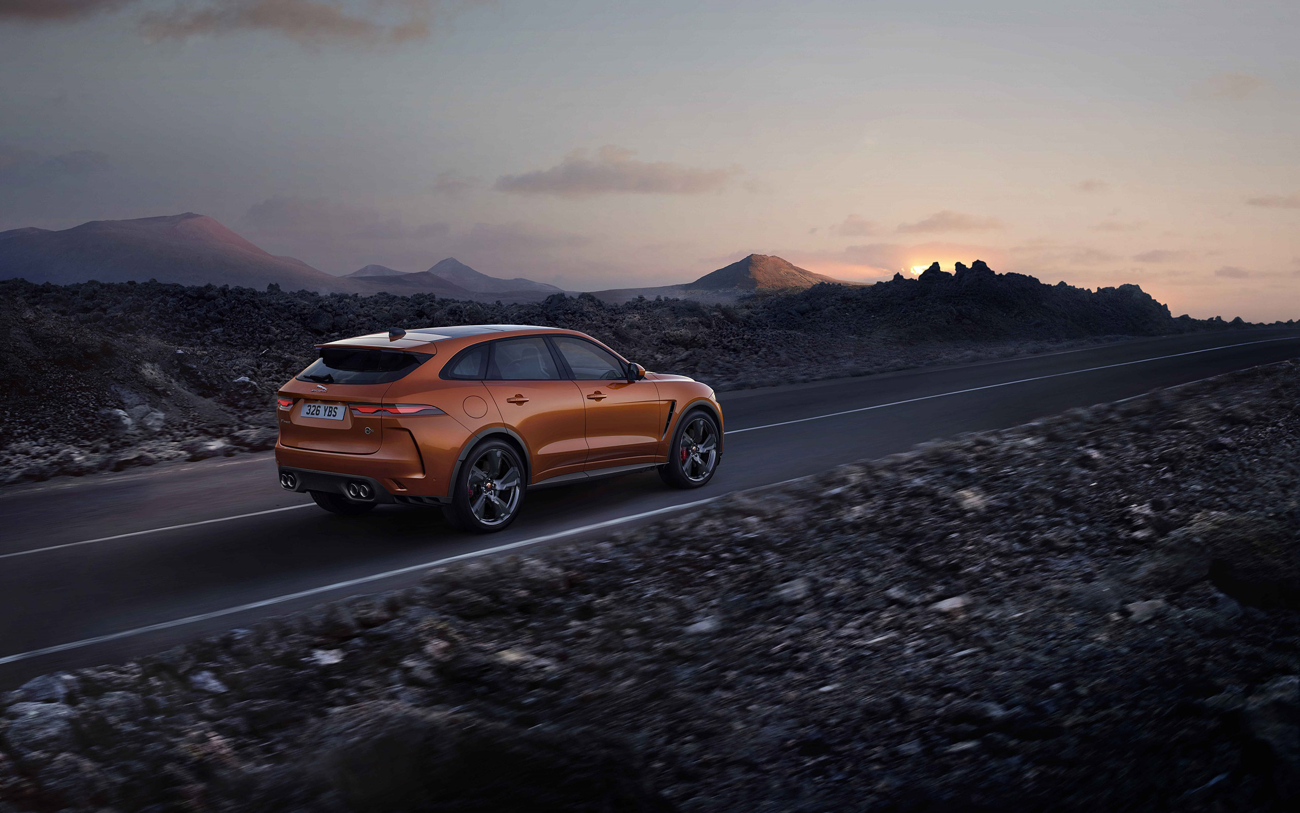 Orange Jaguar F-Pace SVR driving on a road at sunset HD Wallpaper