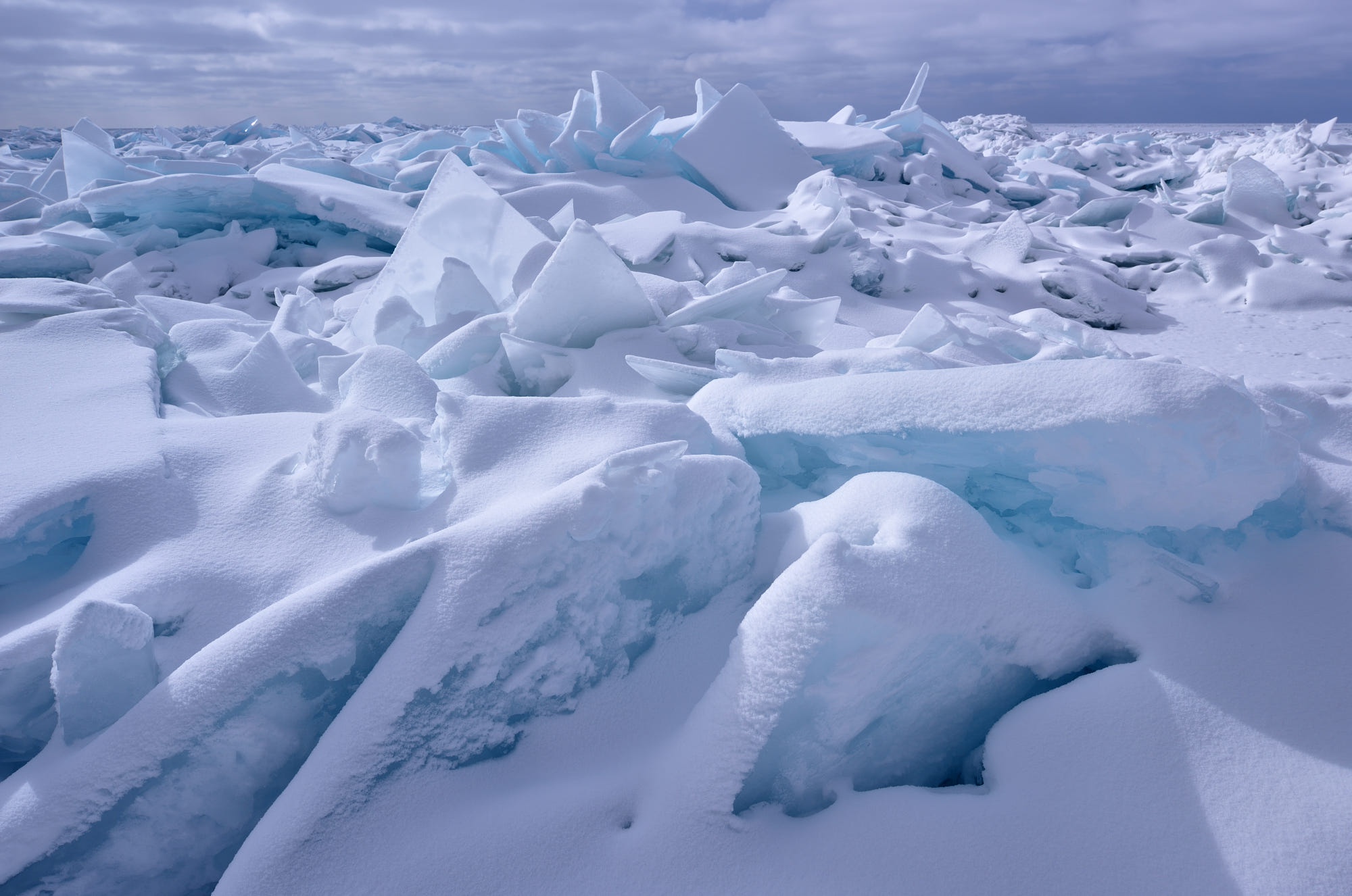 Broken ice floes covered in snow under a cloudy sky HD Wallpaper
