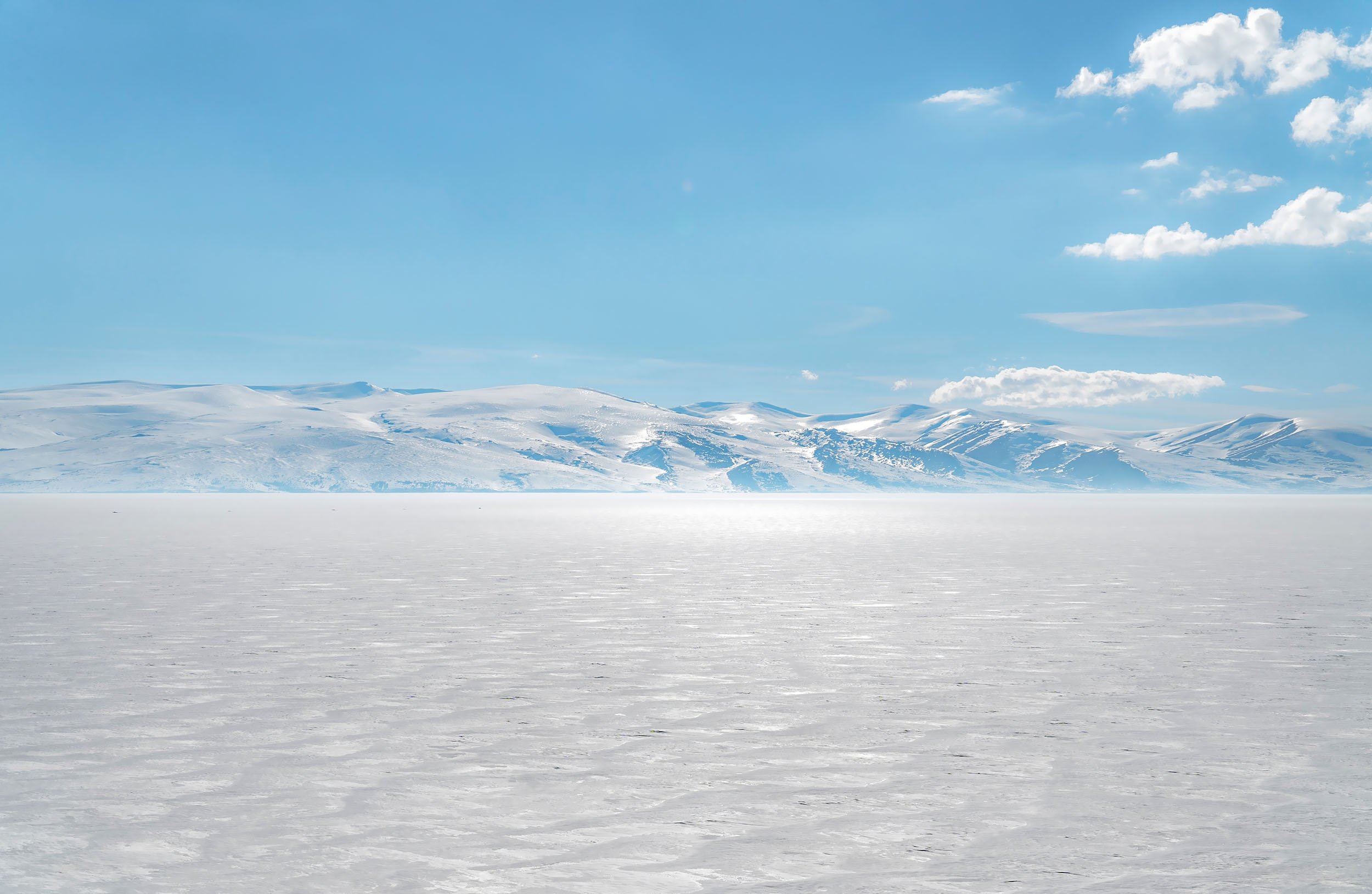Snowy mountains over a frozen lake under a blue sky HD Wallpaper