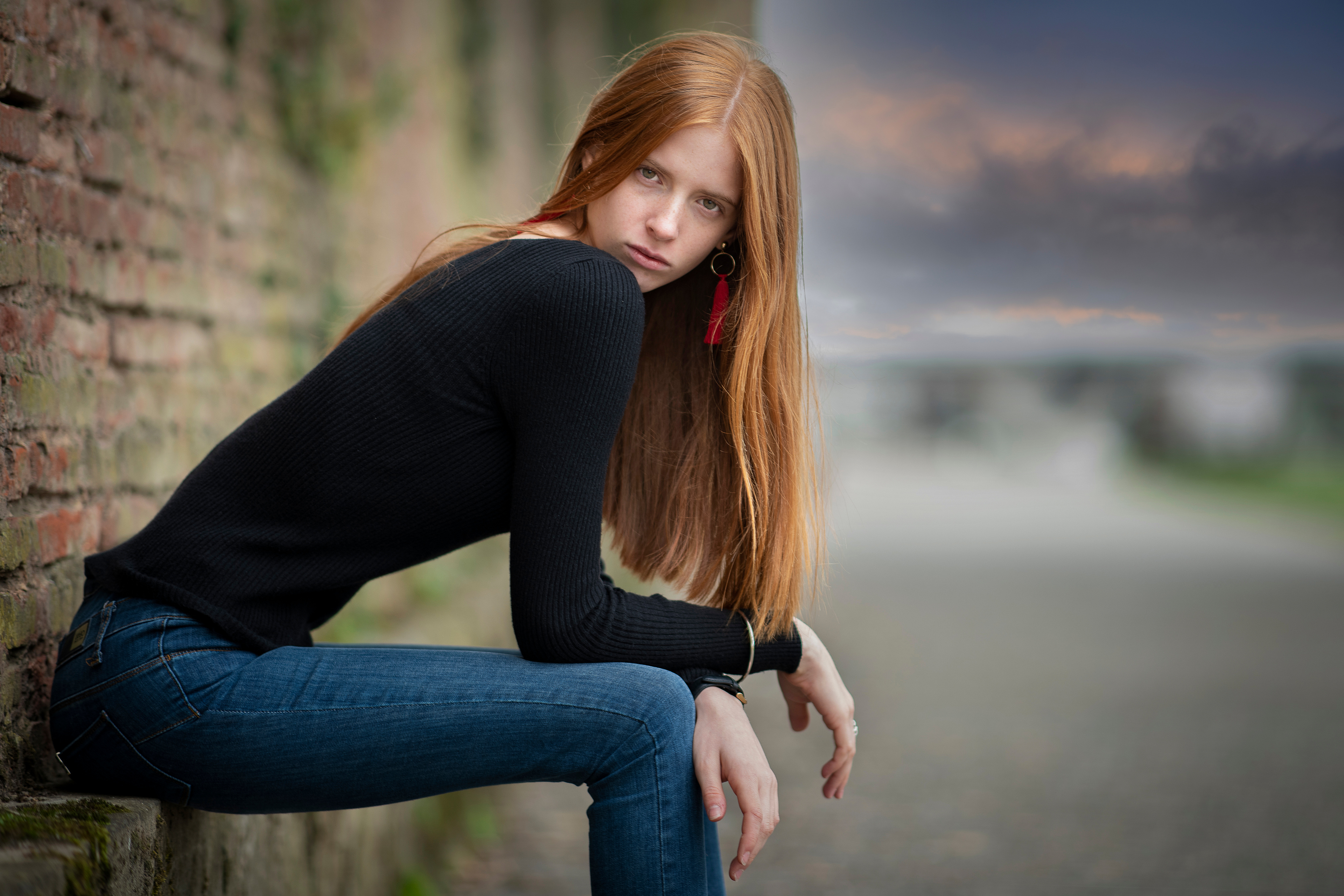 Woman with long red hair sitting by a brick wall HD Wallpaper