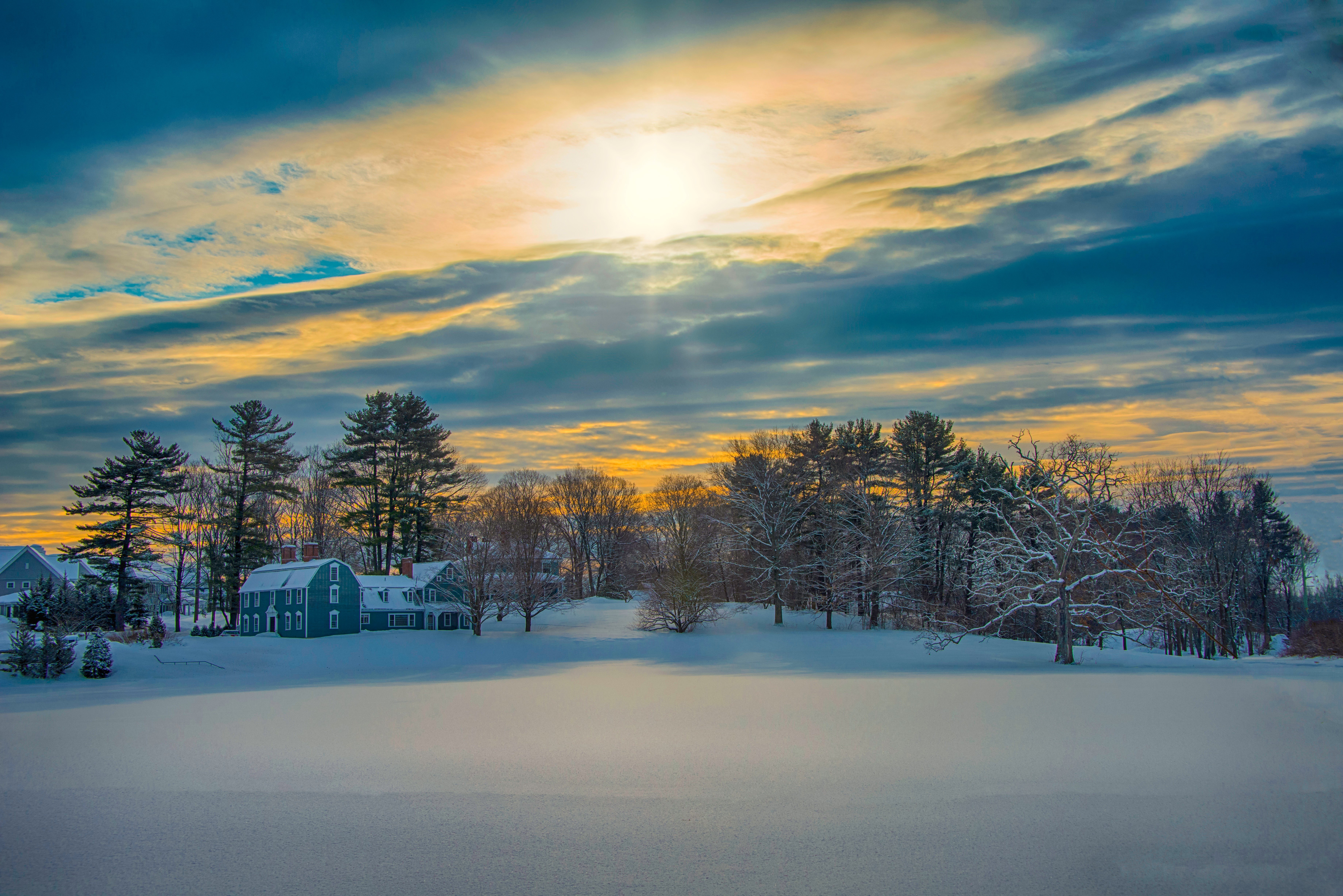 Winter sunset over a snow-covered landscape with houses and trees HD Wallpaper