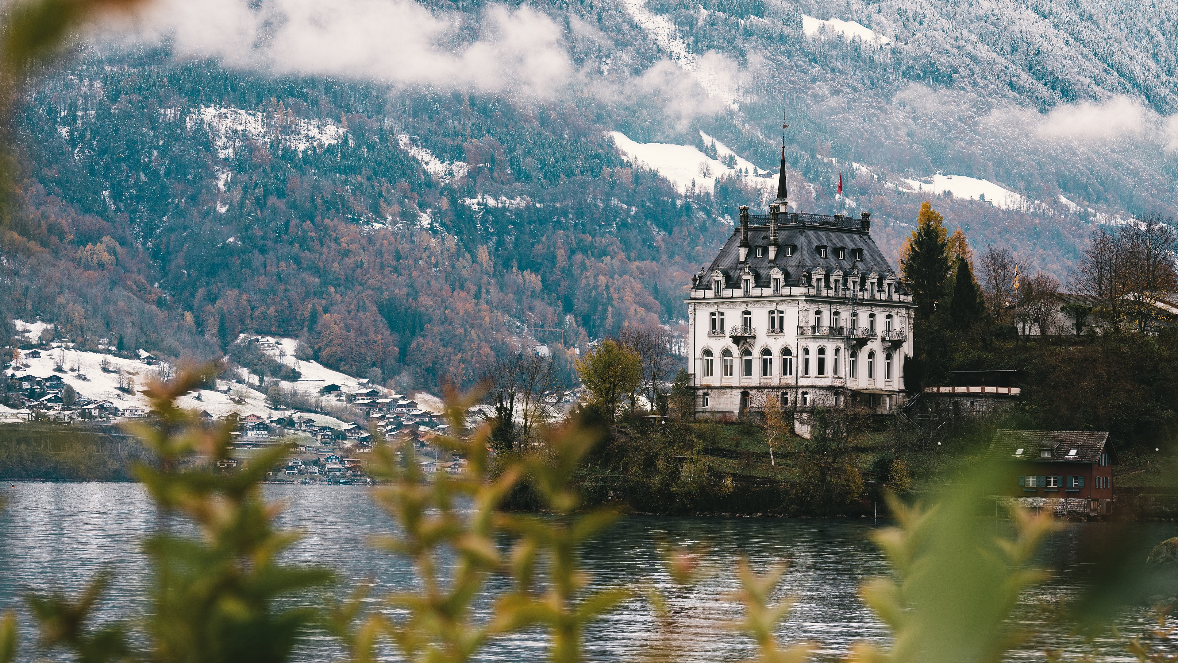 Castle on a hill overlooking a lake with mountains HD Wallpaper