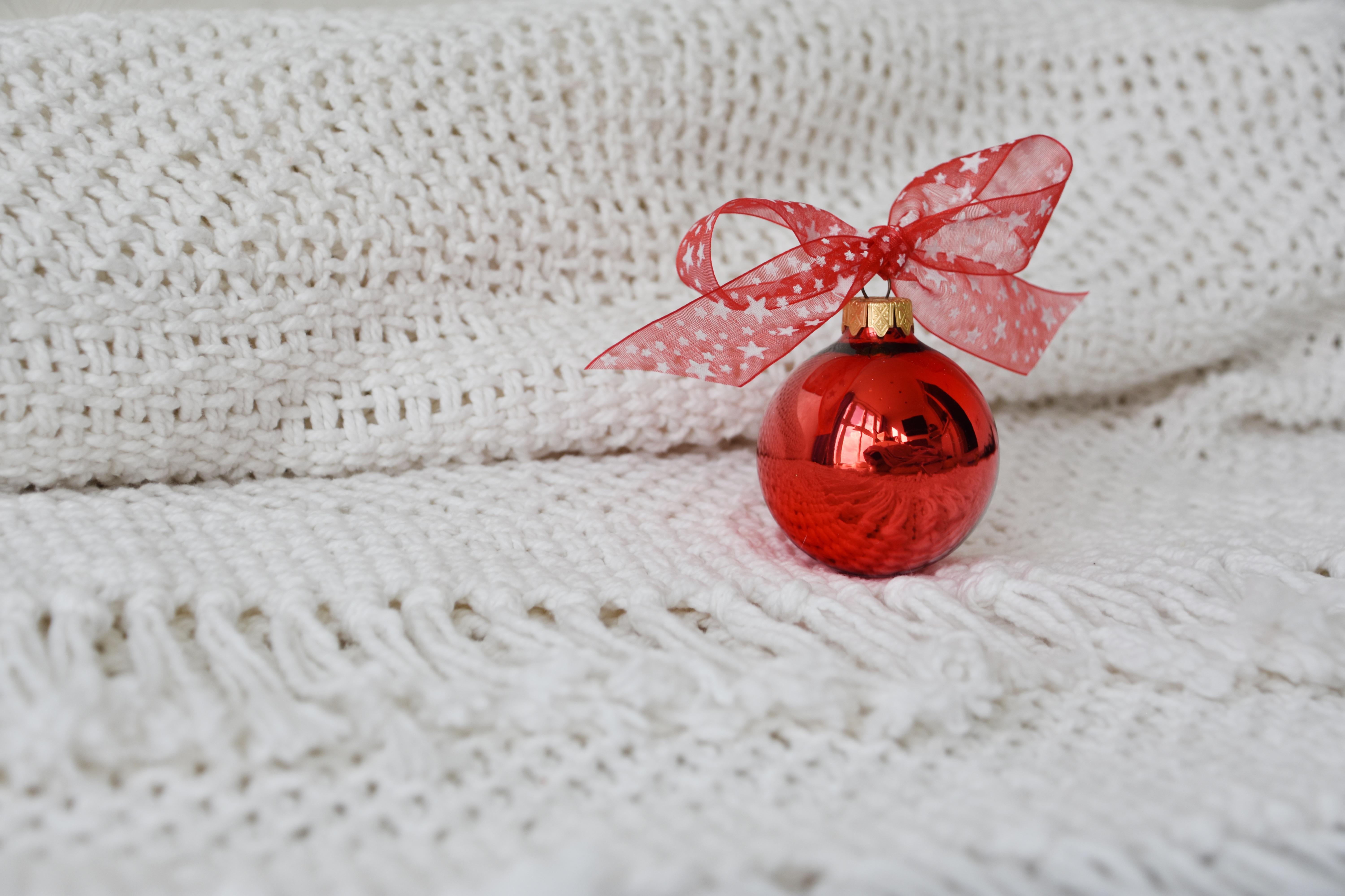 Red Christmas Ornament with Red Bow on White Blanket HD Wallpaper
