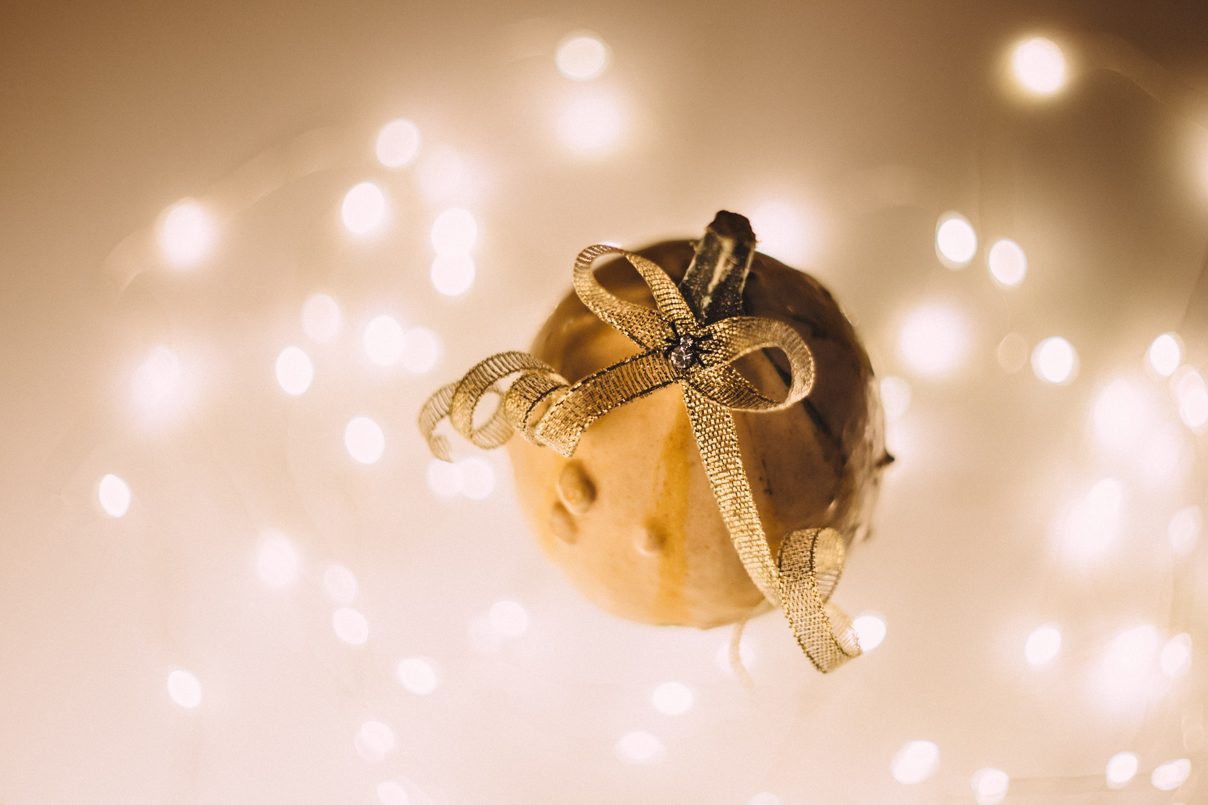 Small pumpkin with a golden bow and bokeh lights HD Wallpaper
