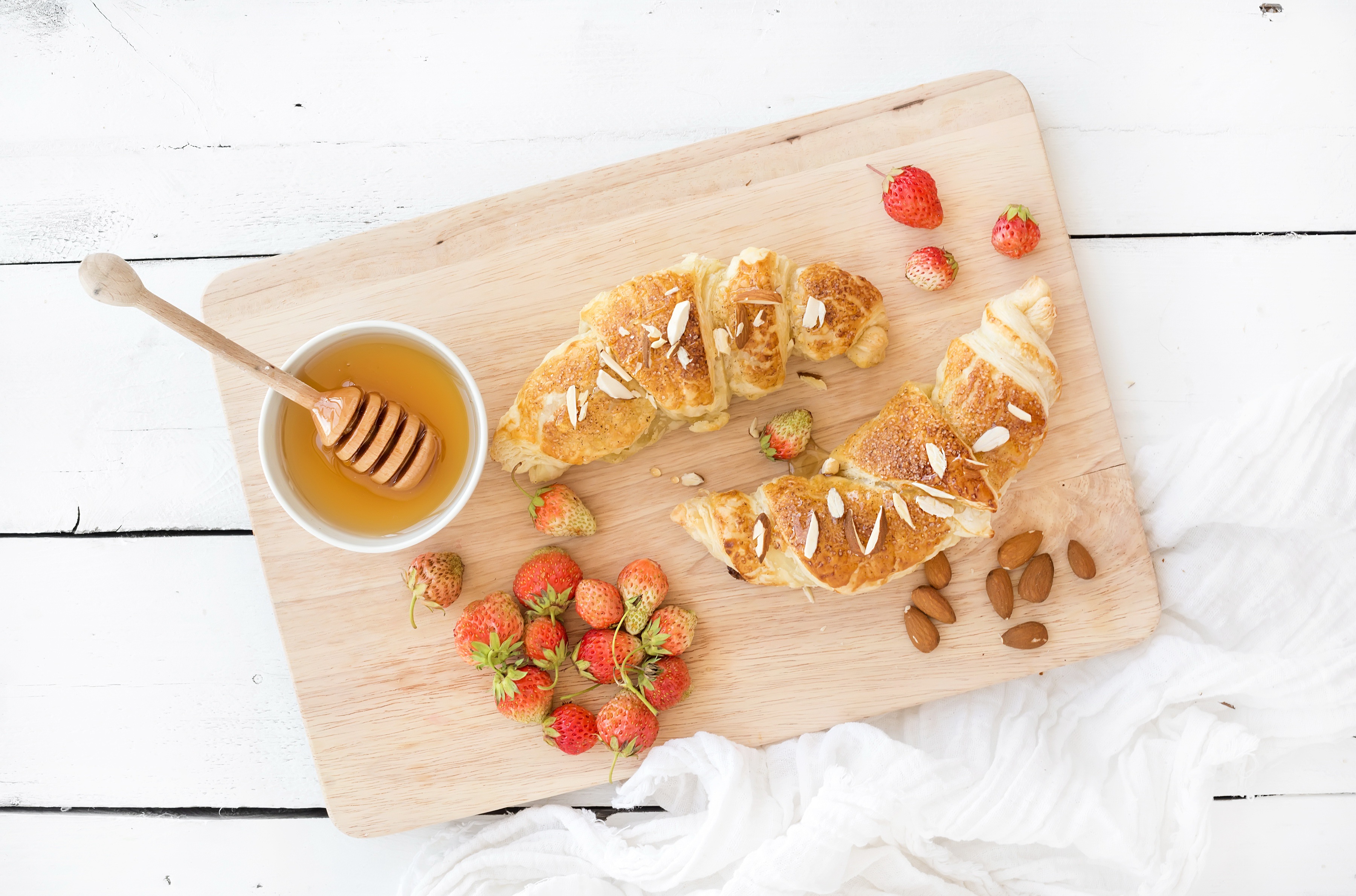 Croissants with strawberries and honey on a wooden board HD Wallpaper