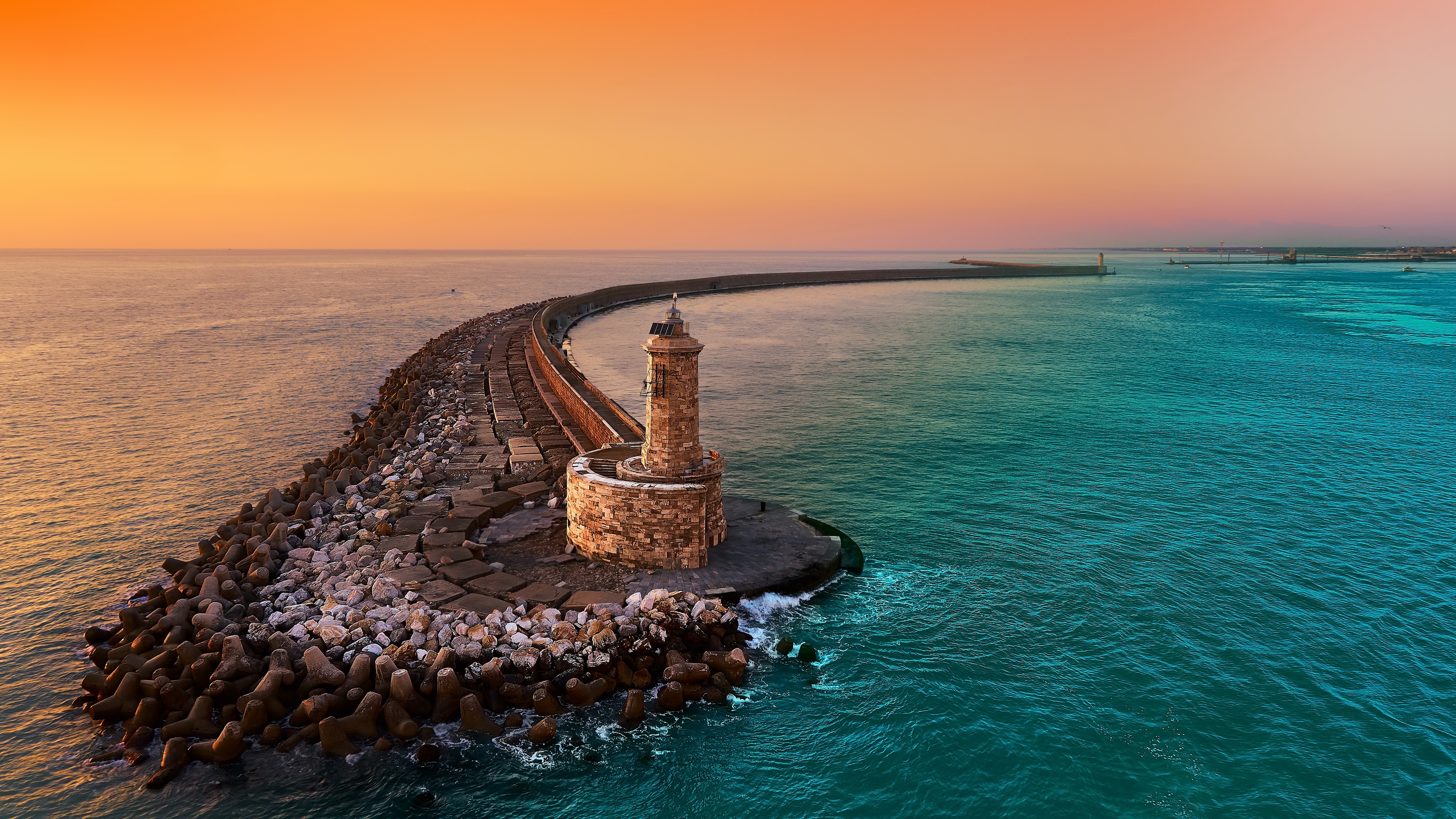 Lighthouse on a breakwater at sunset HD Wallpaper