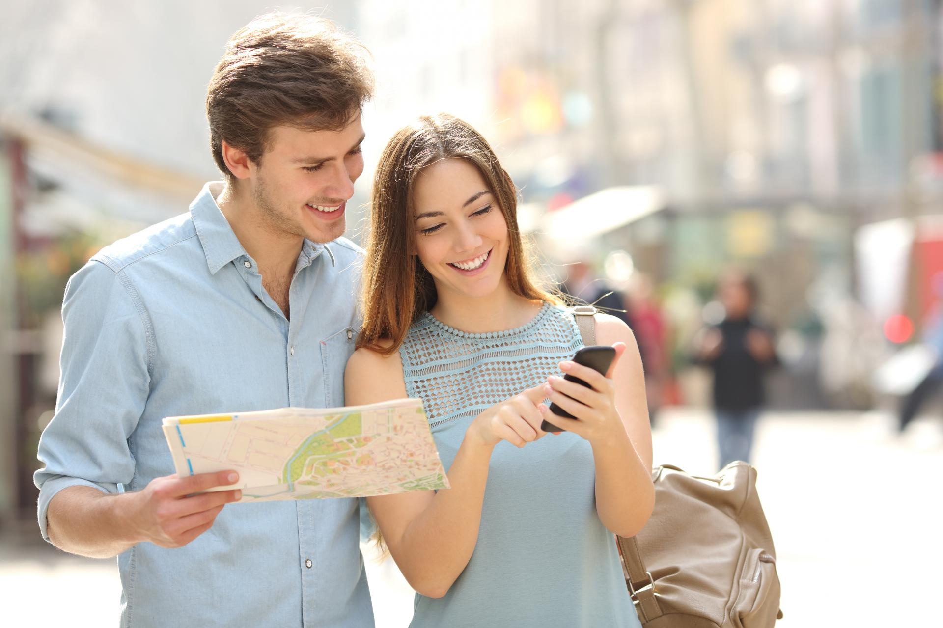 Couple looking at map and phone on street HD Wallpaper