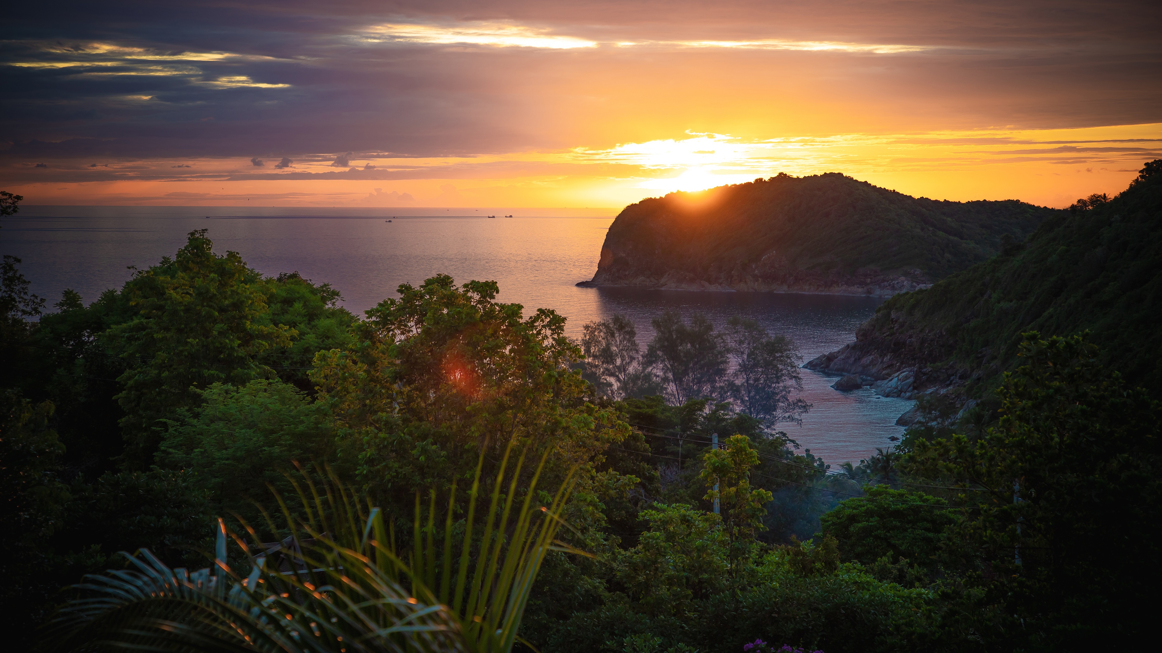 Sunset over a tropical coastline with lush vegetation HD Wallpaper