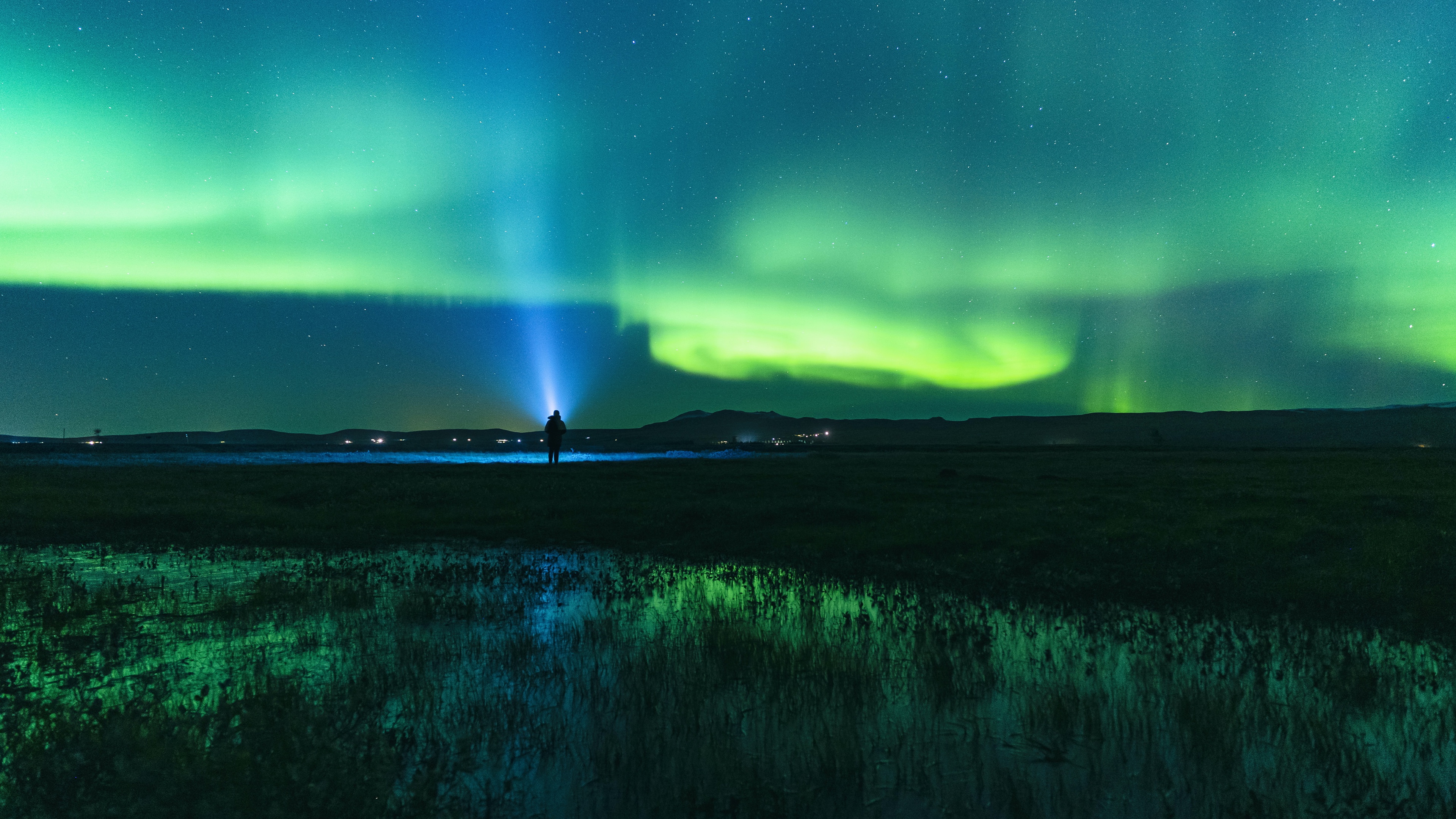 Man with flashlight watching Aurora Borealis in Iceland HD Wallpaper