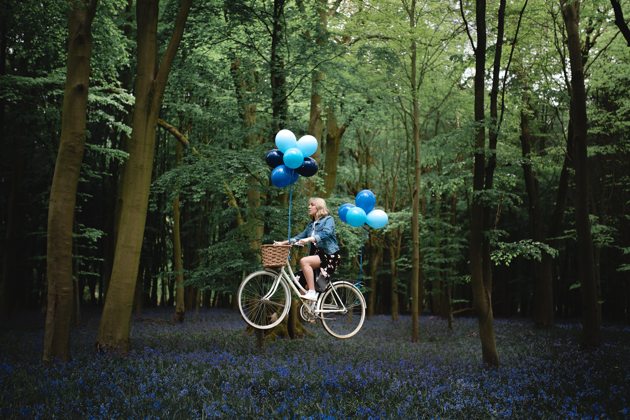 Woman on bicycle flying with balloons in forest HD Wallpaper