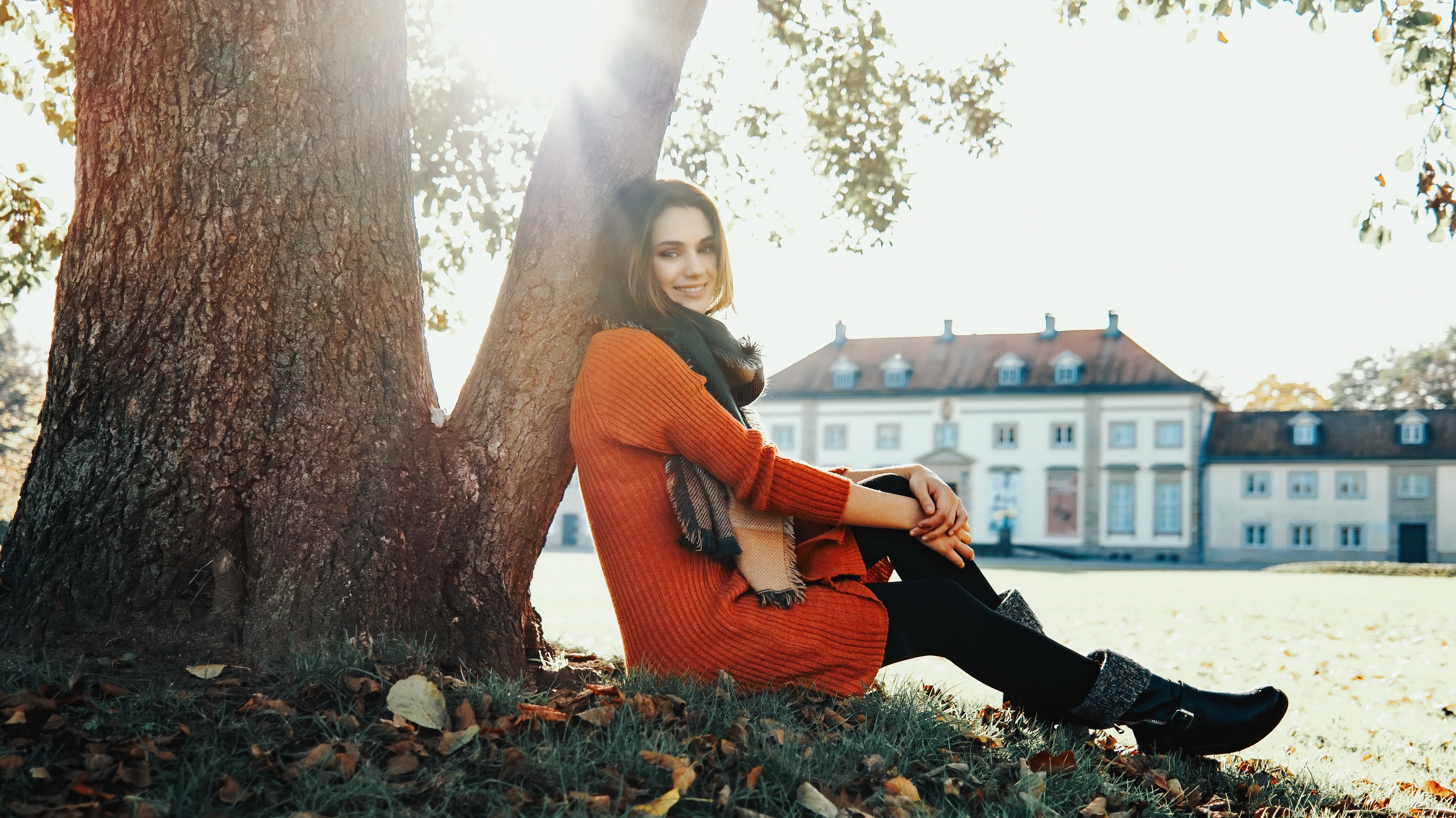 Smiling Model Sitting by Tree in Sunlight HD Wallpaper