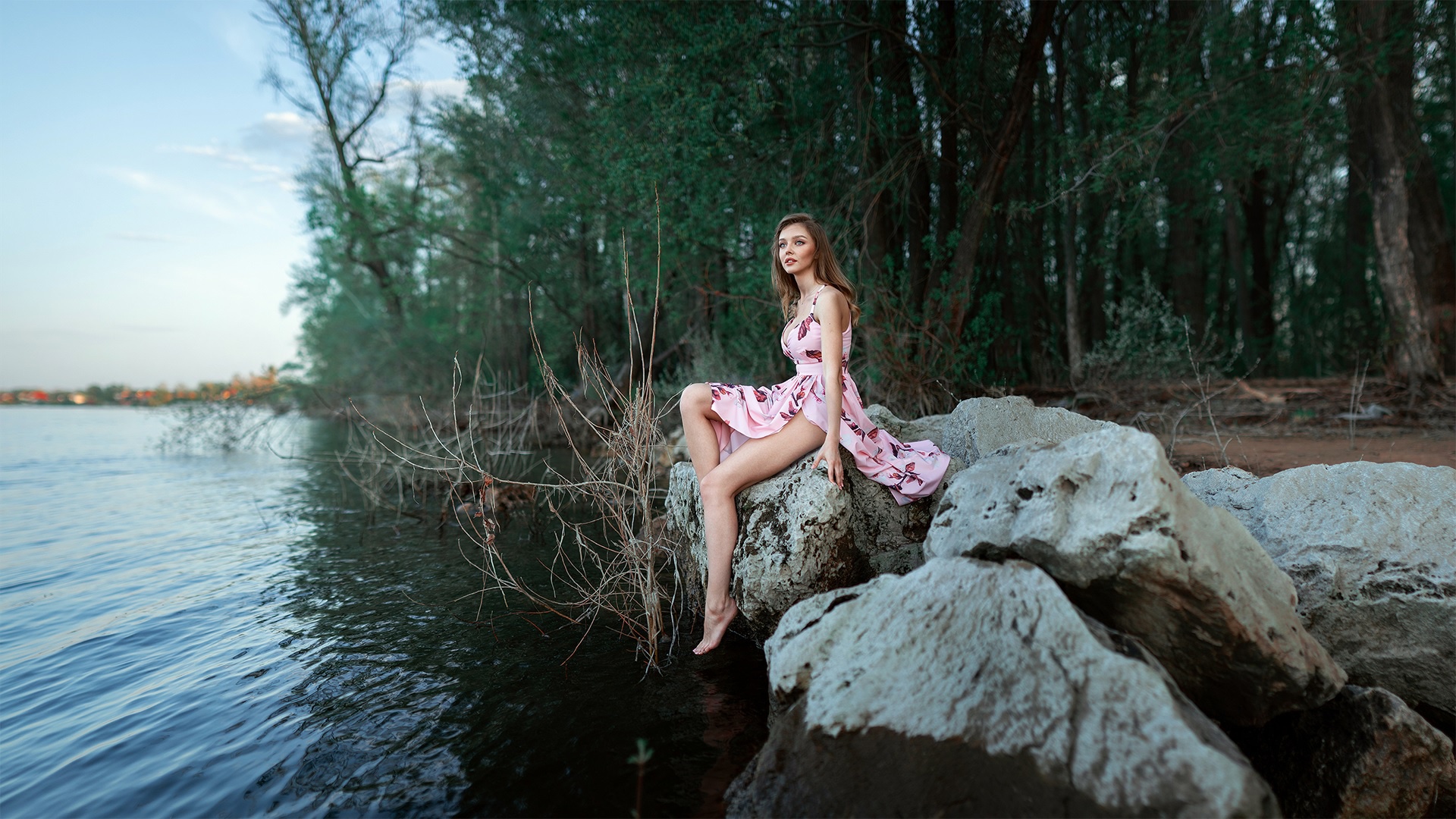 Woman in Pink Dress Sitting on Rocks by Lake HD Wallpaper