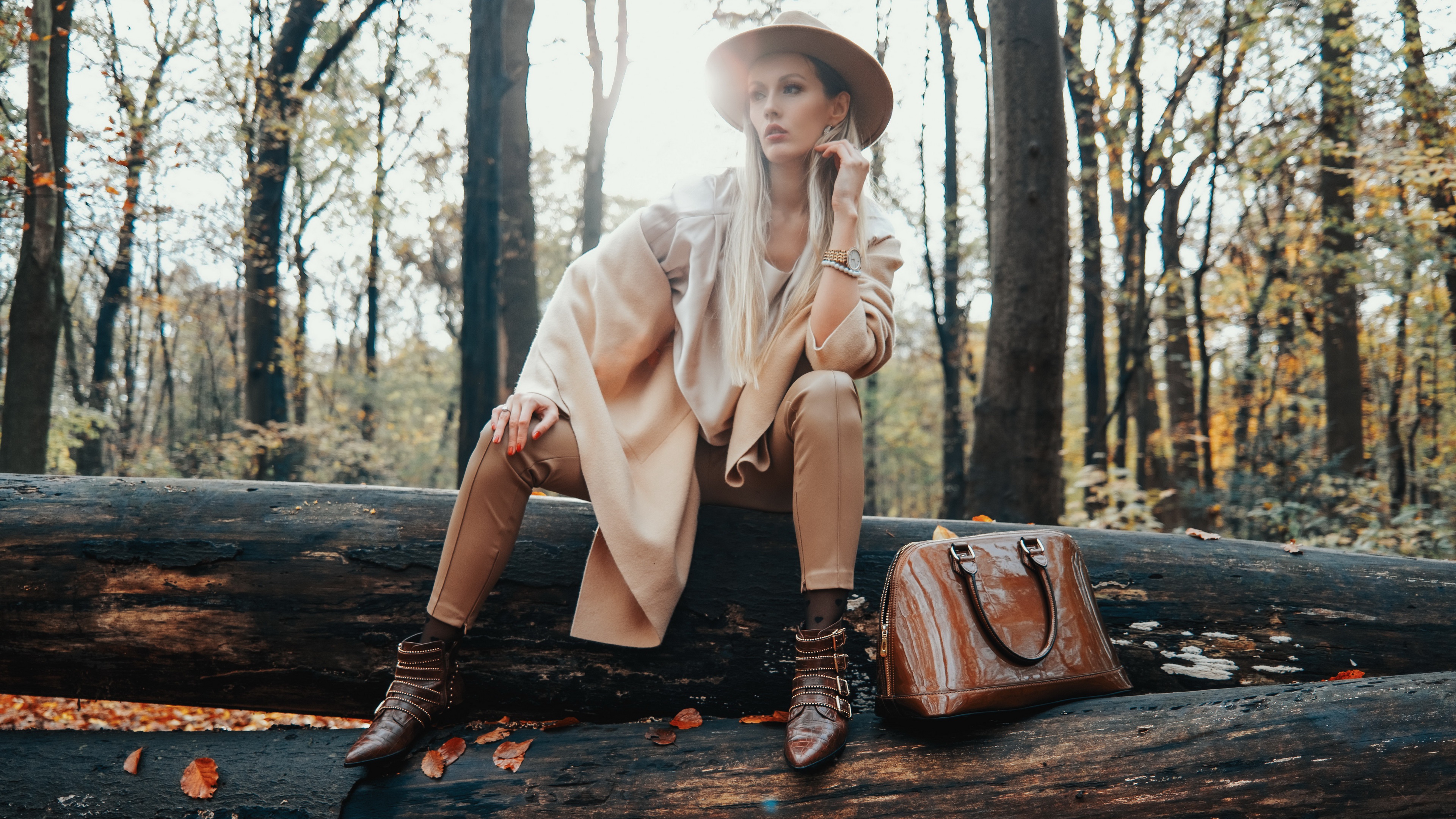 Woman in hat and coat sitting on a log HD Wallpaper