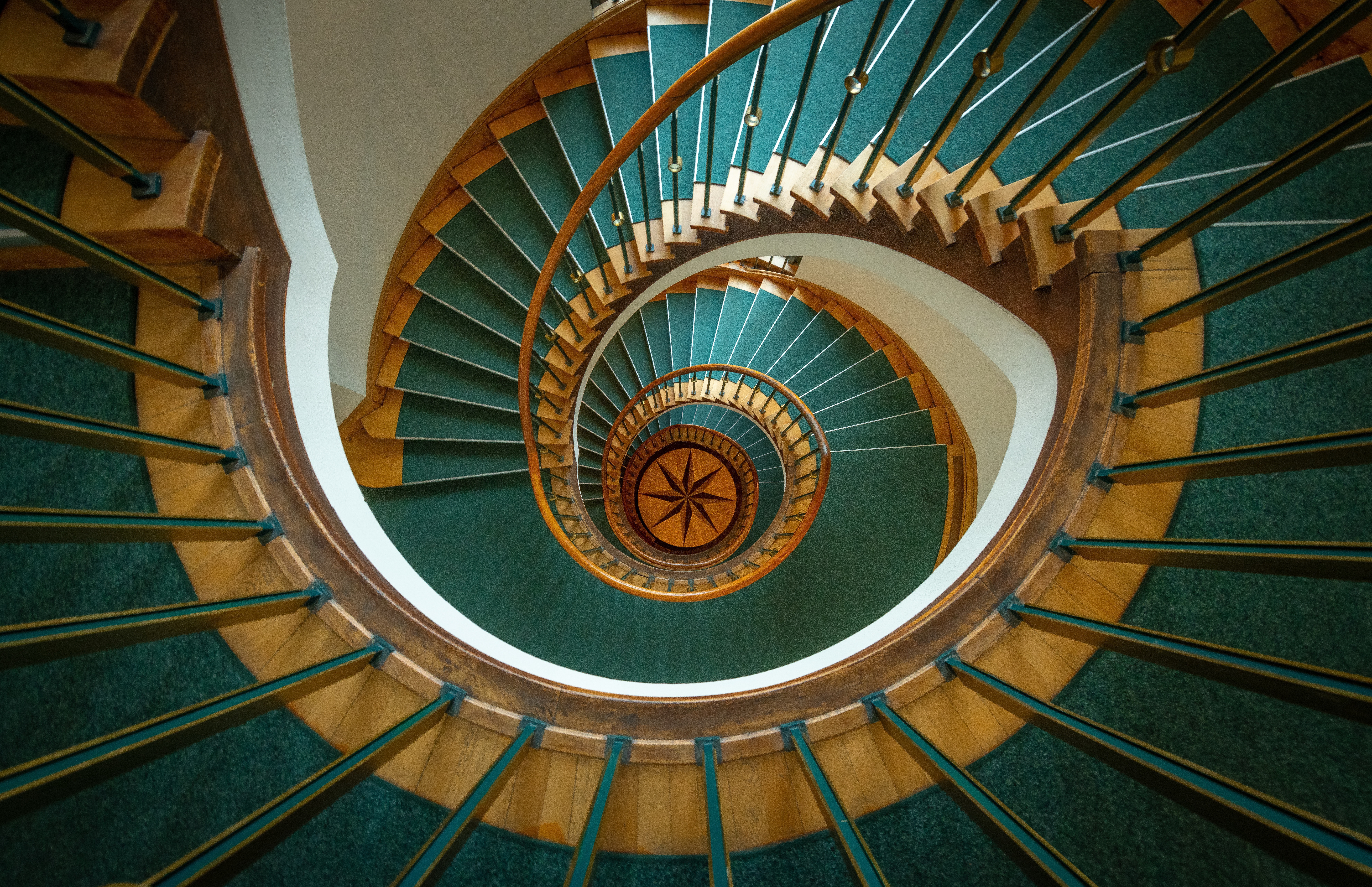 Spiral staircase with green carpet and wooden accents HD Wallpaper
