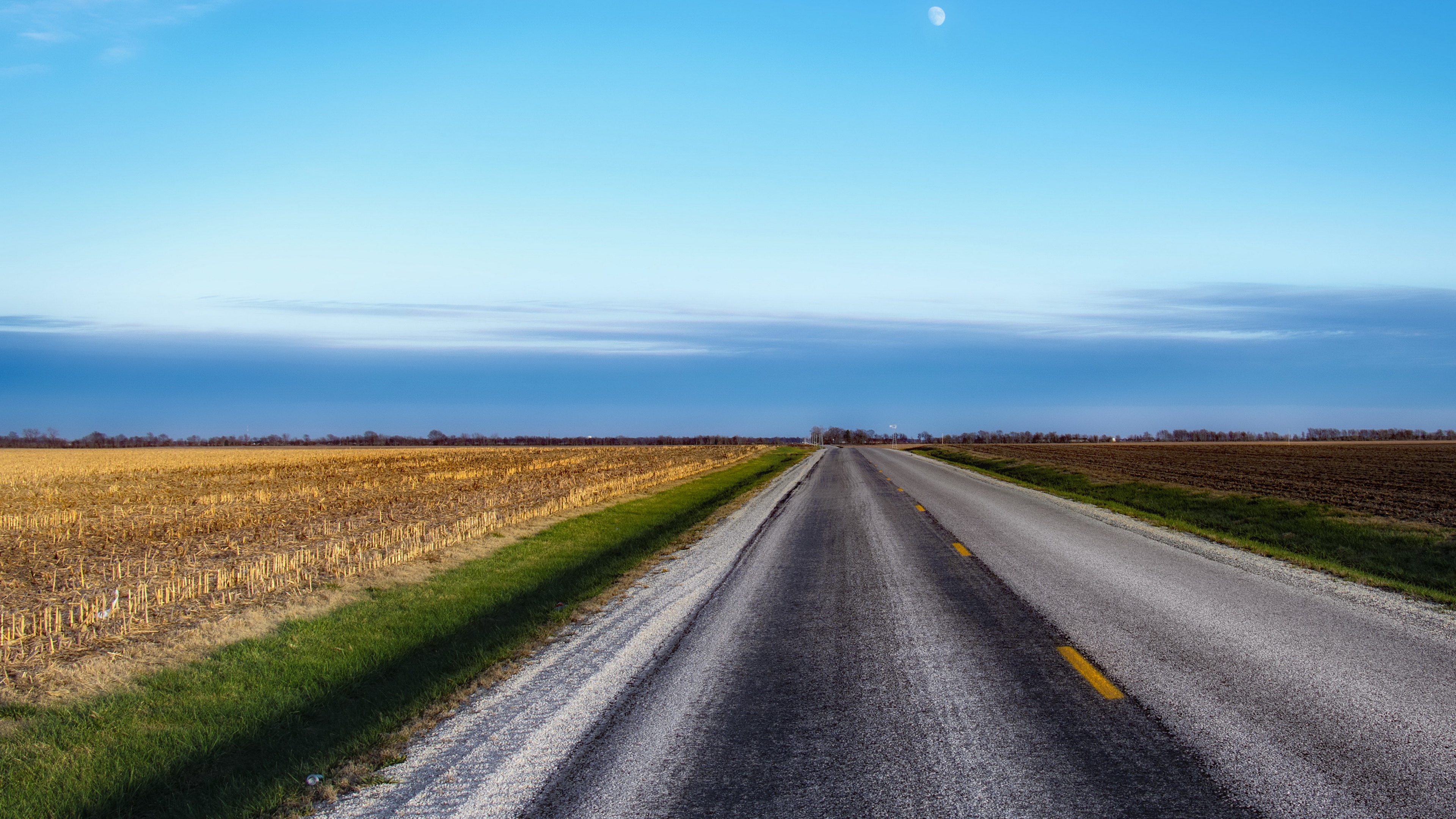 Road through fields under a blue sky with moon HD Wallpaper