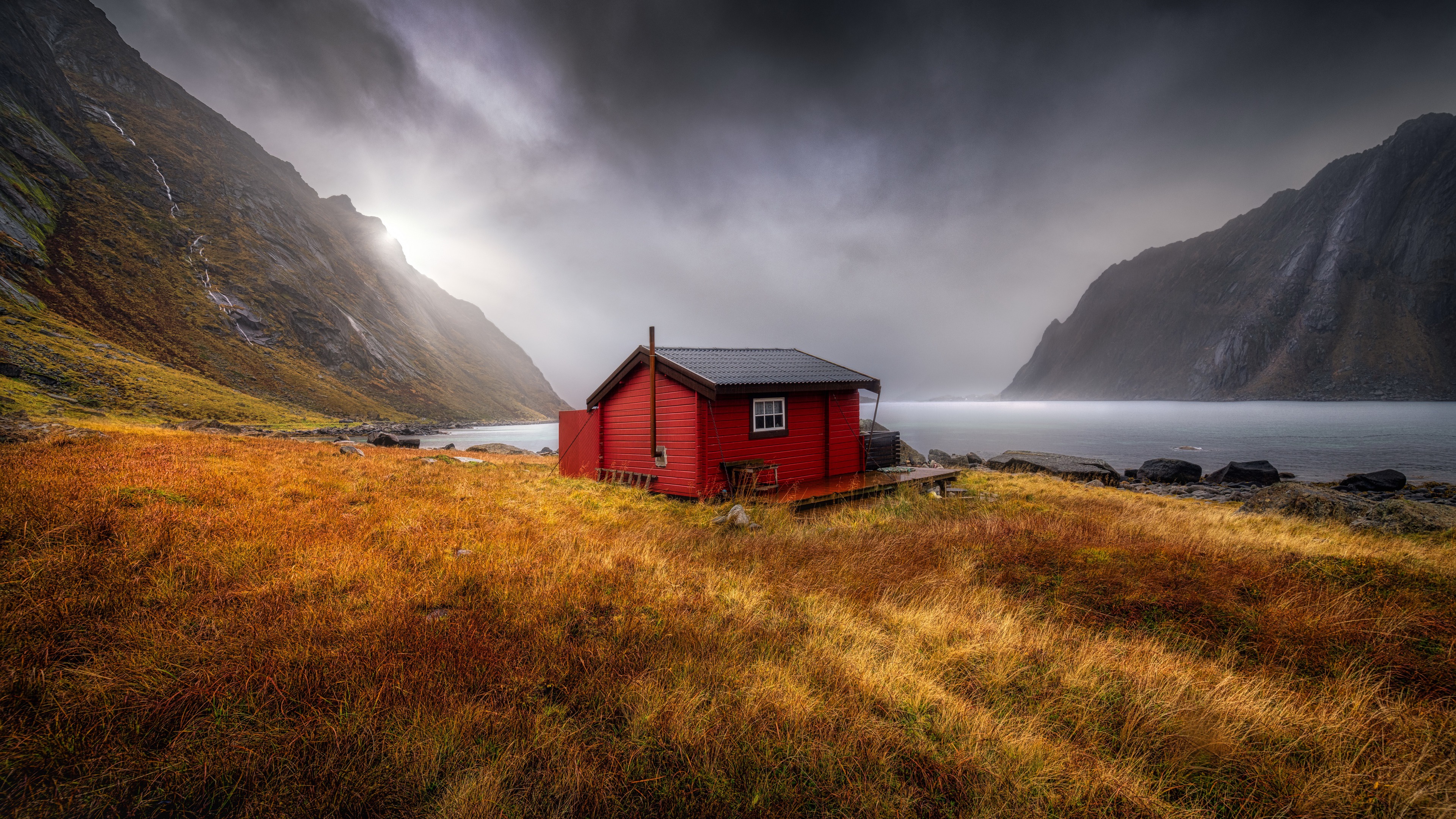 Red cabin on a rocky shore with mountains HD Wallpaper