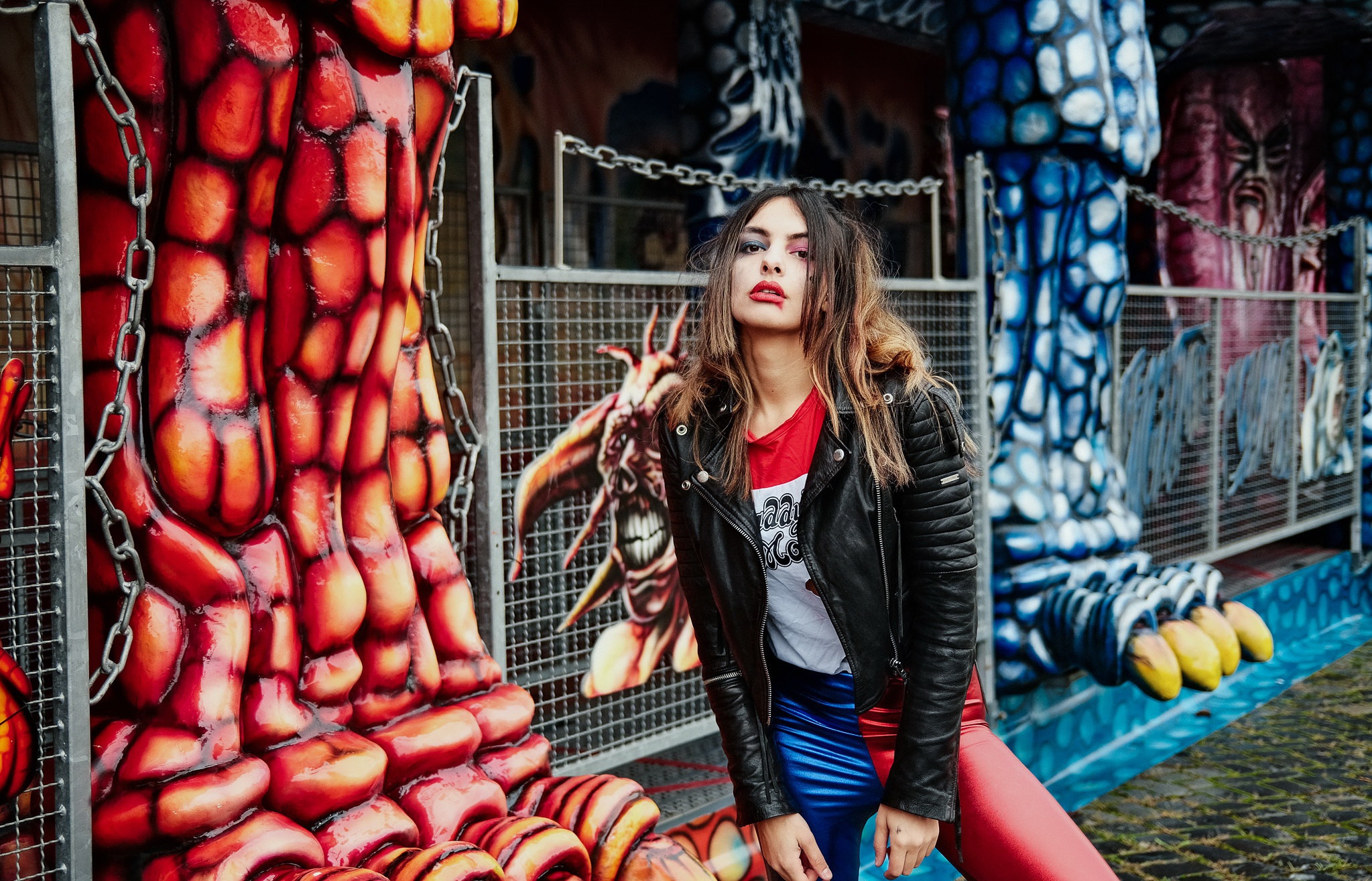 Woman in leather jacket and colorful pants at amusement park HD Wallpaper