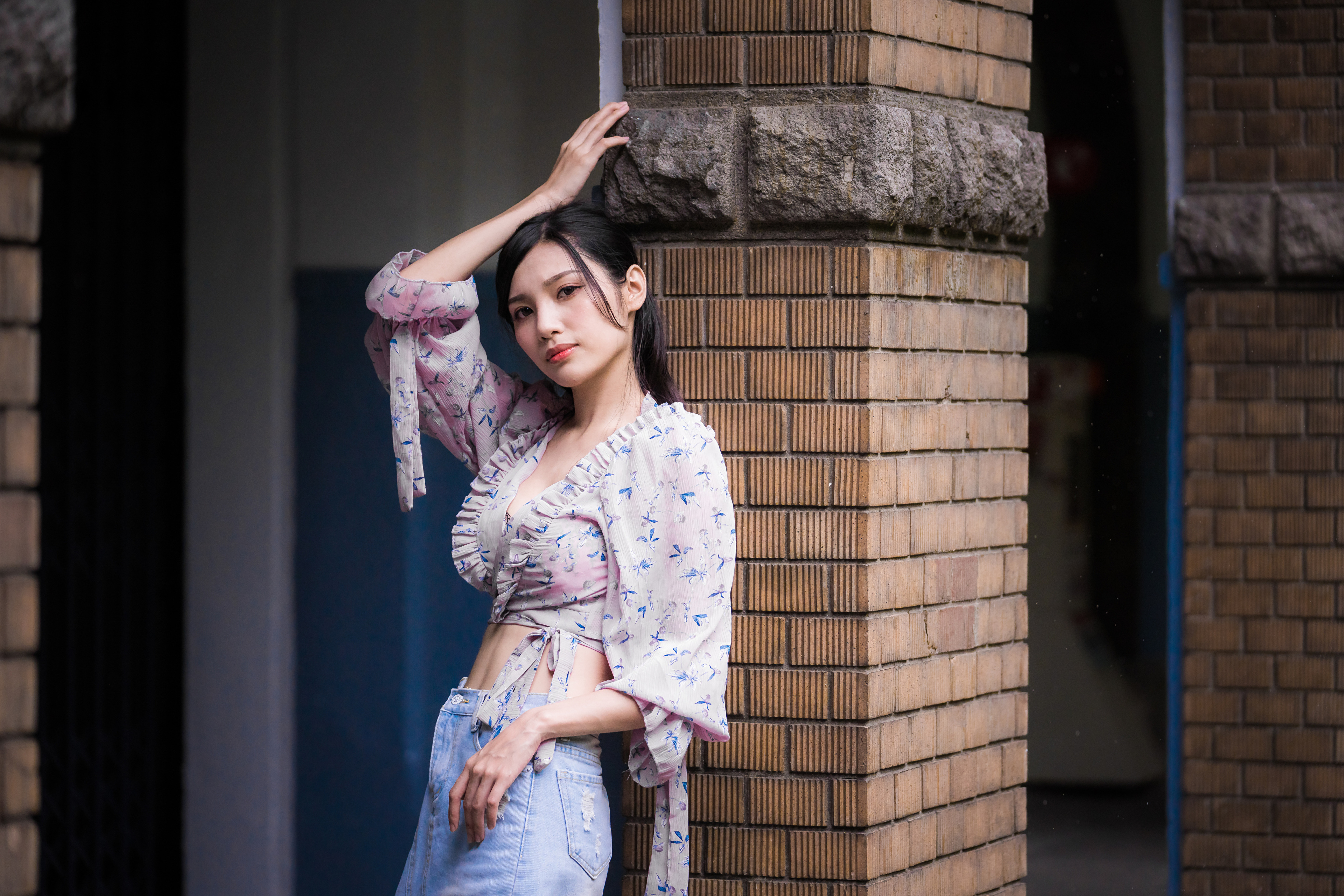 Asian woman with black hair leaning against a brick pillar HD Wallpaper
