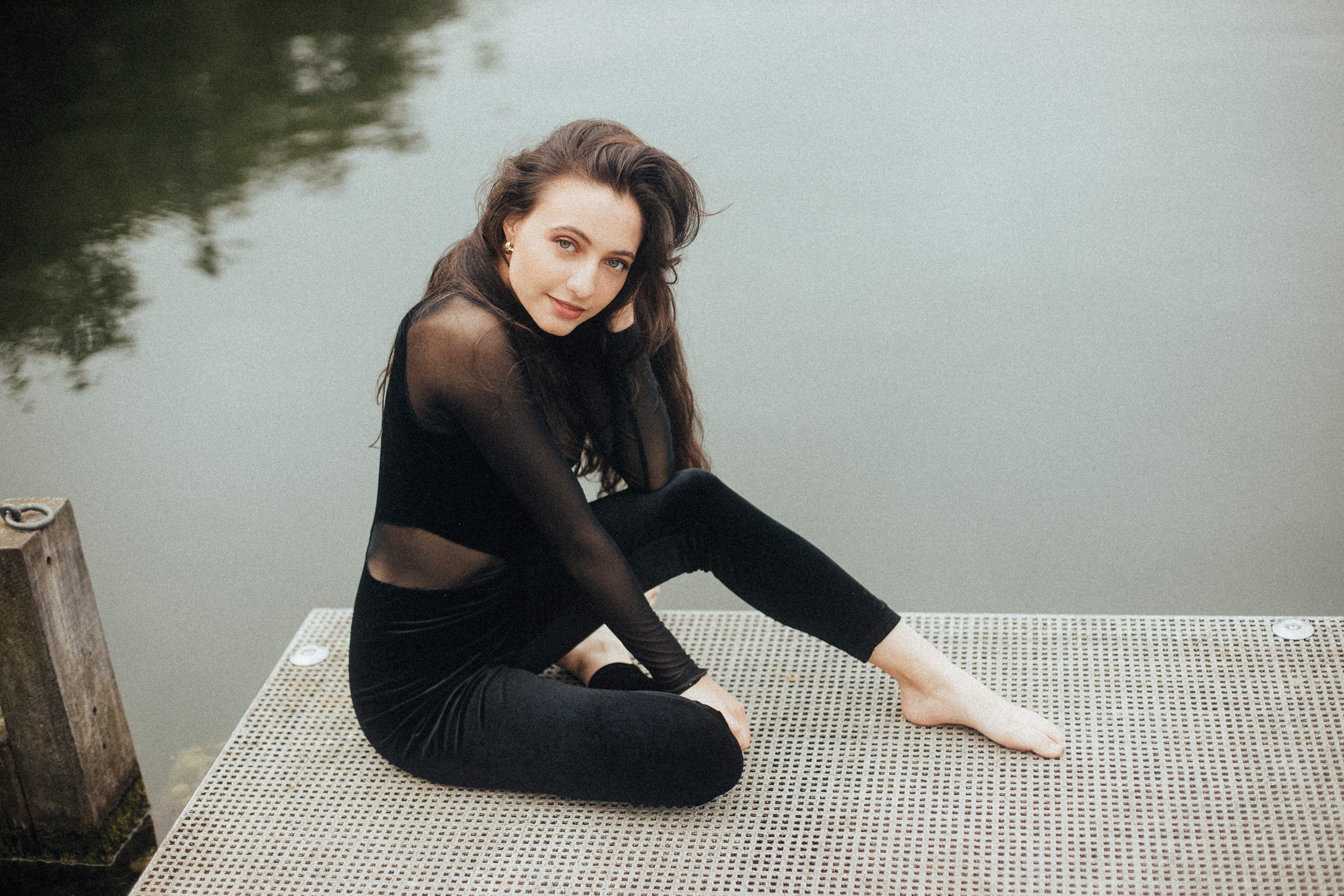 Woman in black outfit sitting by water HD Wallpaper