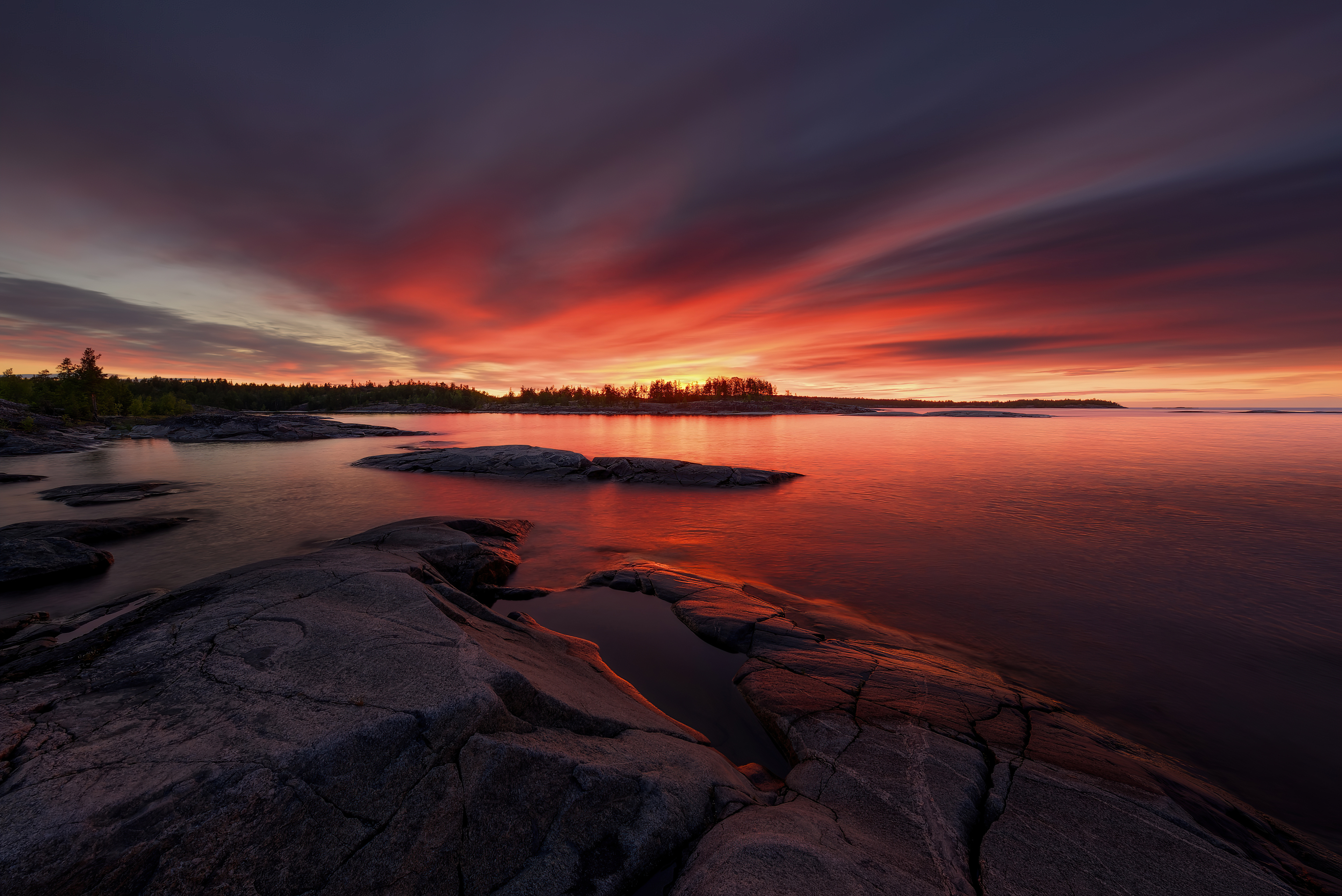 Dramatic sunset over rocky shore and calm water HD Wallpaper