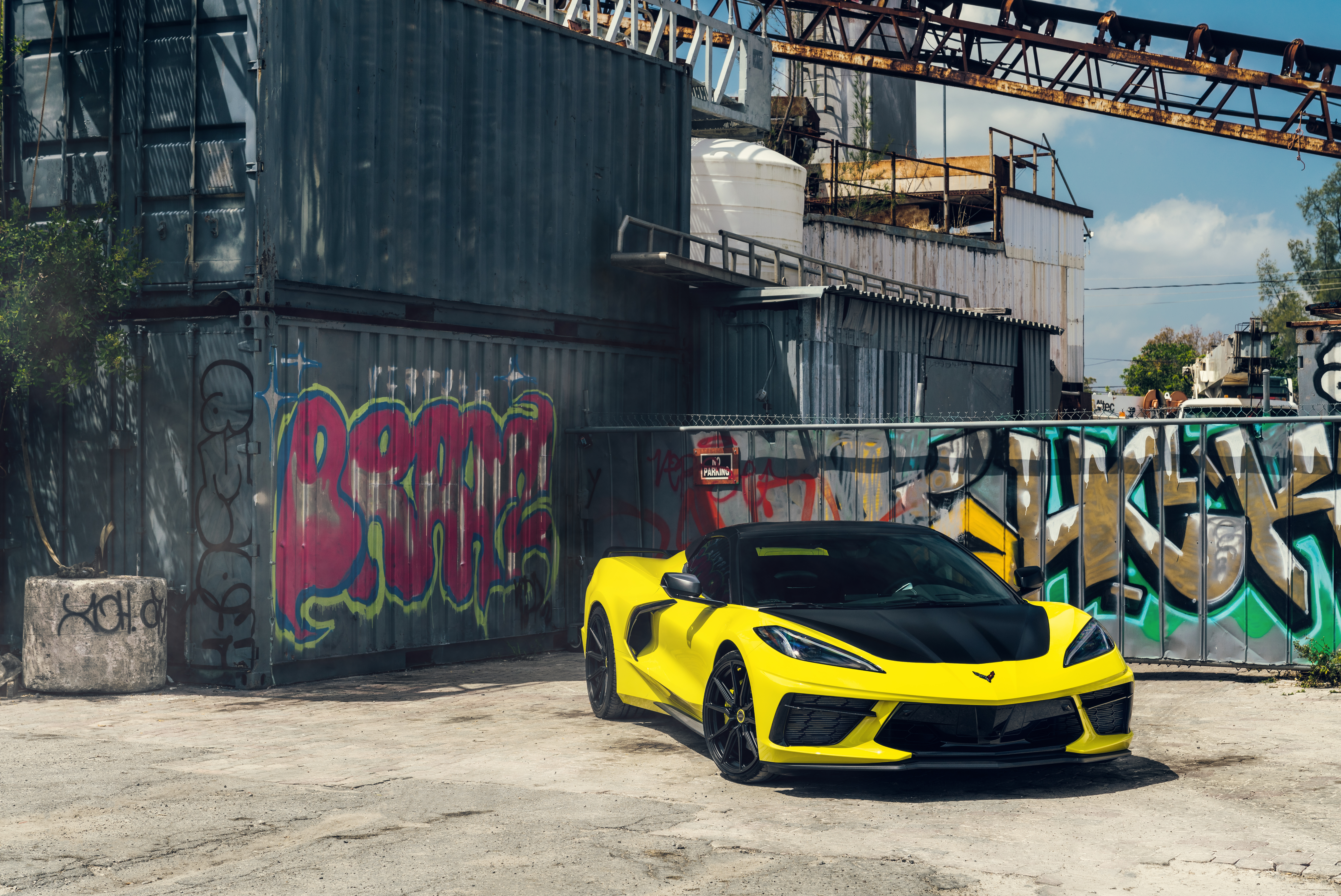 Yellow Chevrolet Corvette C8 parked near graffiti containers HD Wallpaper