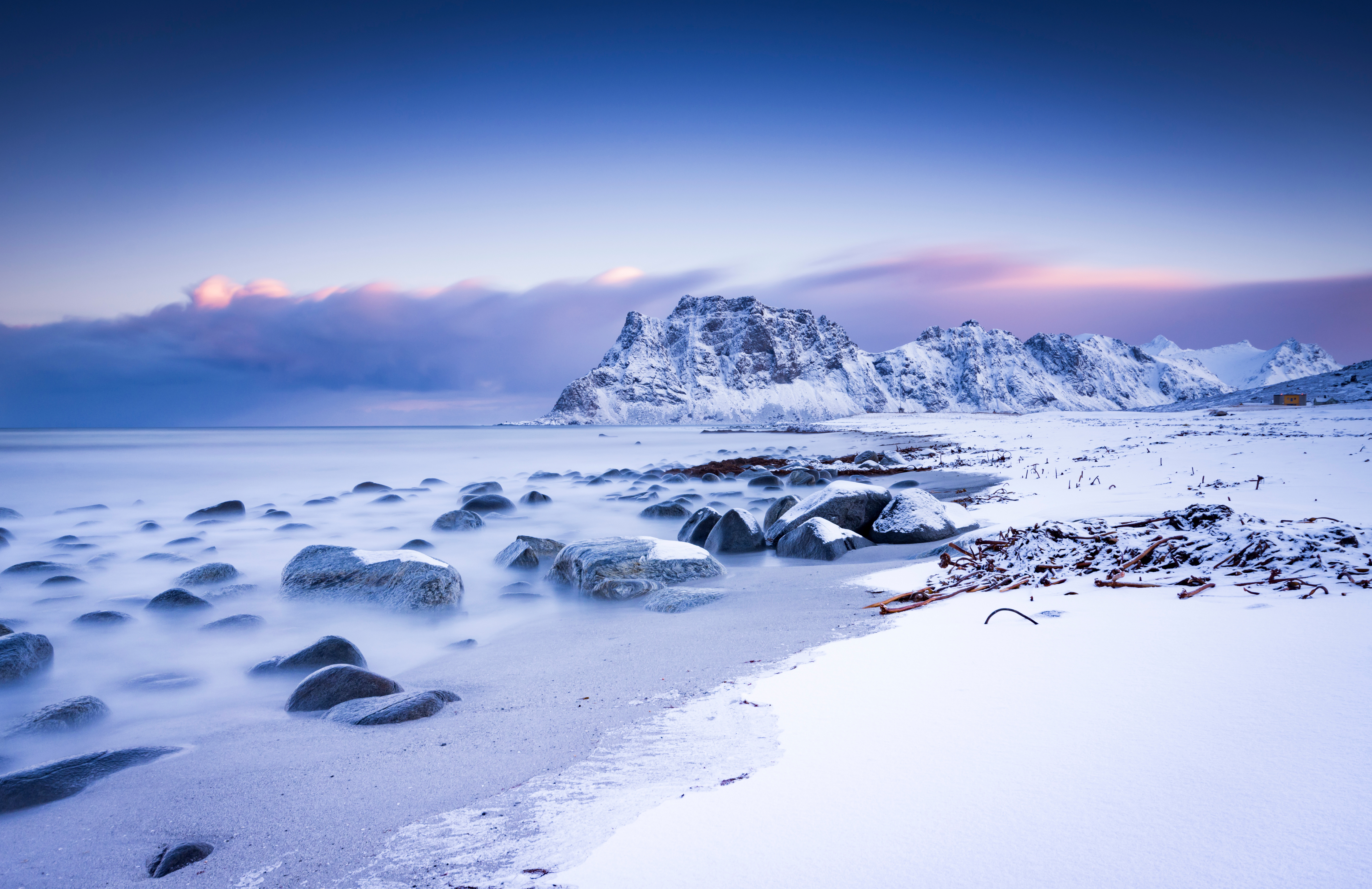Snowy mountains and rocky beach at sunset HD Wallpaper