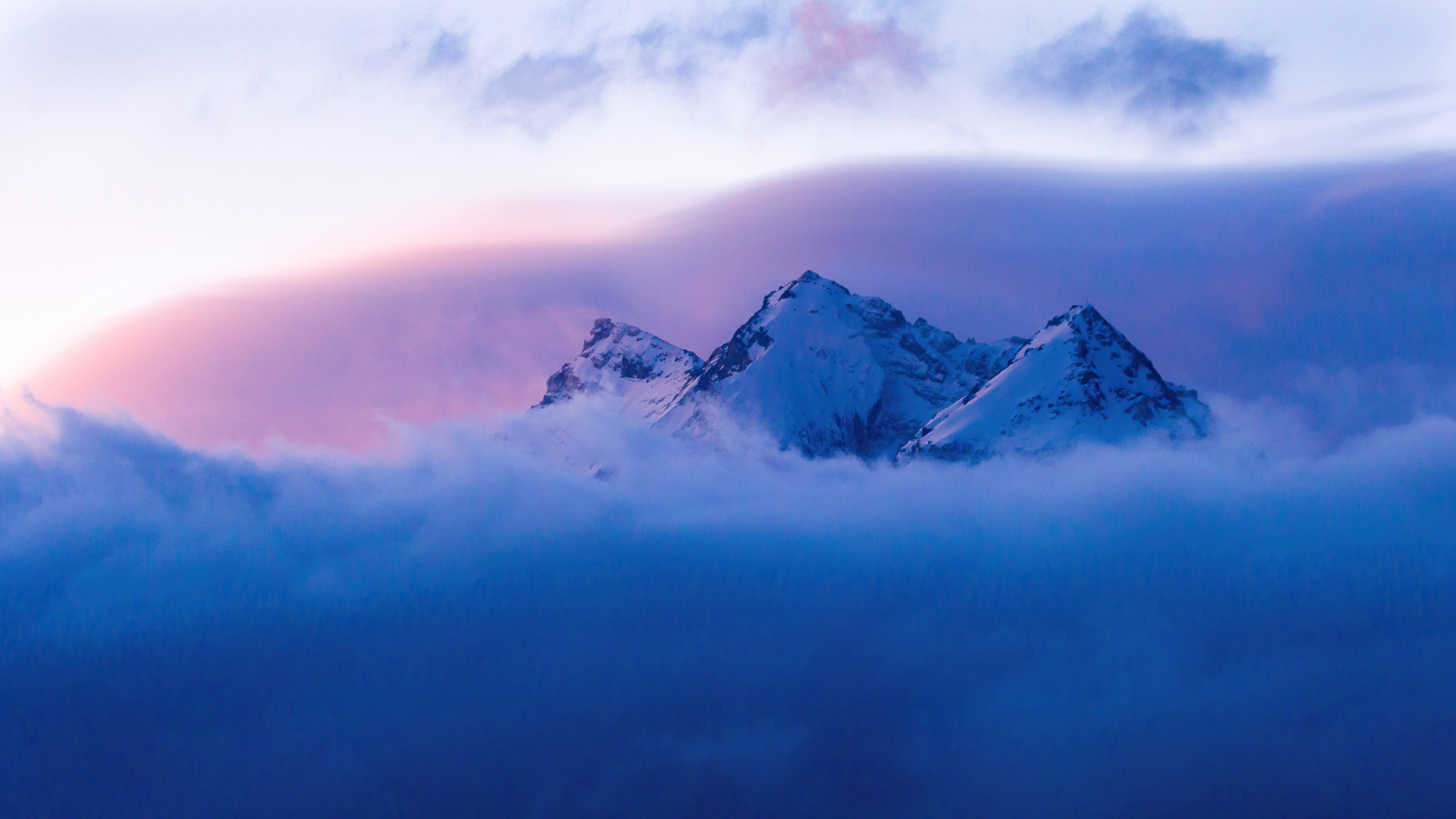 Snowy mountains emerge from clouds at sunrise HD Wallpaper