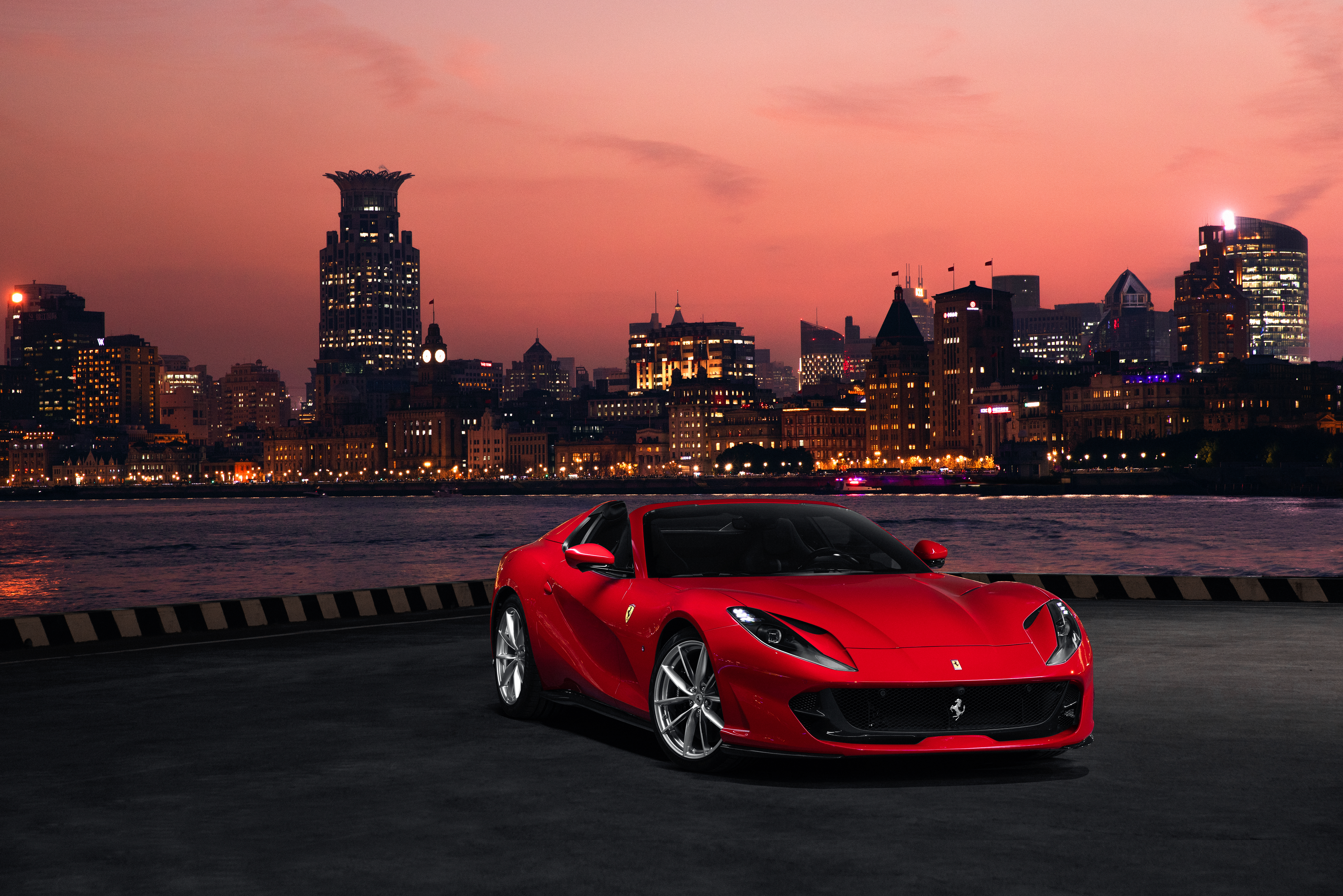 Red Ferrari 812 Superfast parked by a city skyline at dusk HD Wallpaper
