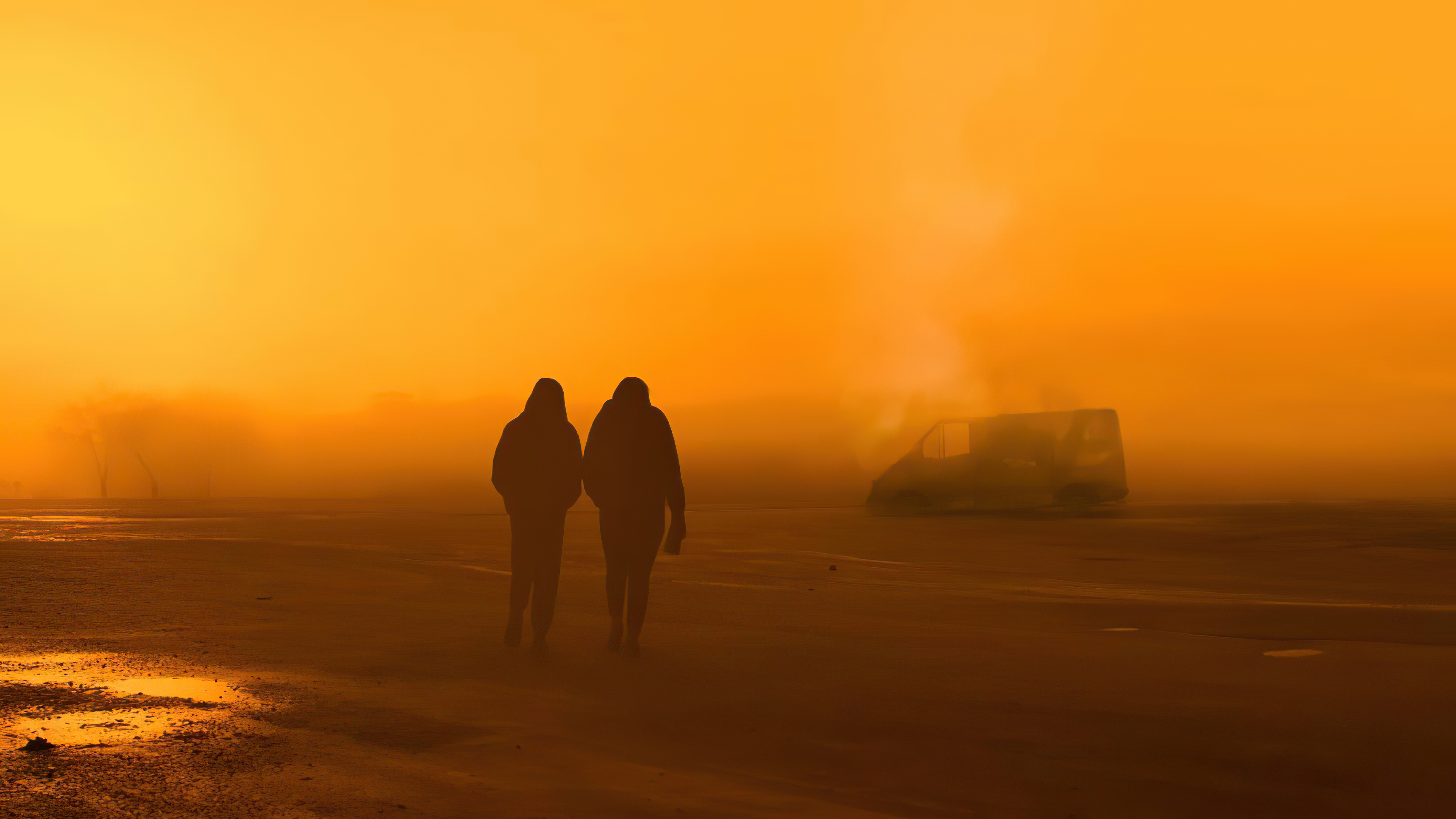 Two people walking in a foggy orange landscape with a van HD Wallpaper