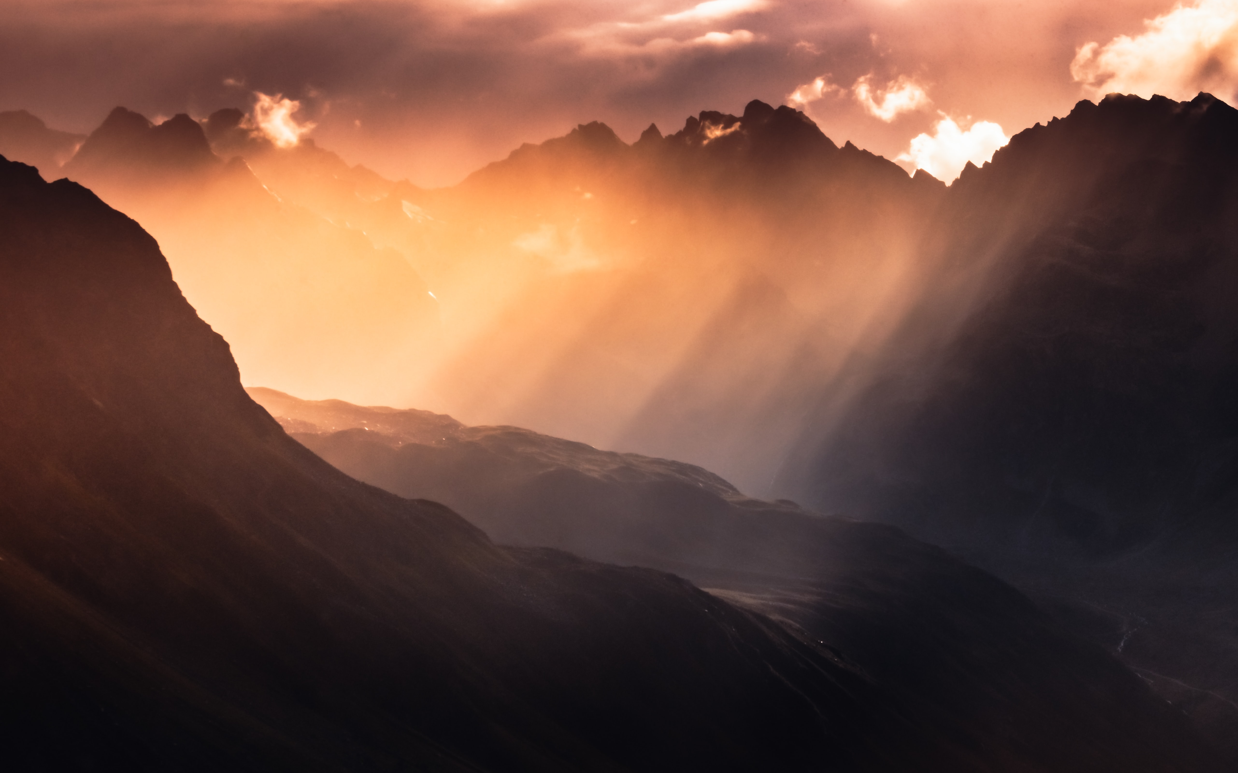 Sunlight beams through clouds over dark mountain peaks HD Wallpaper