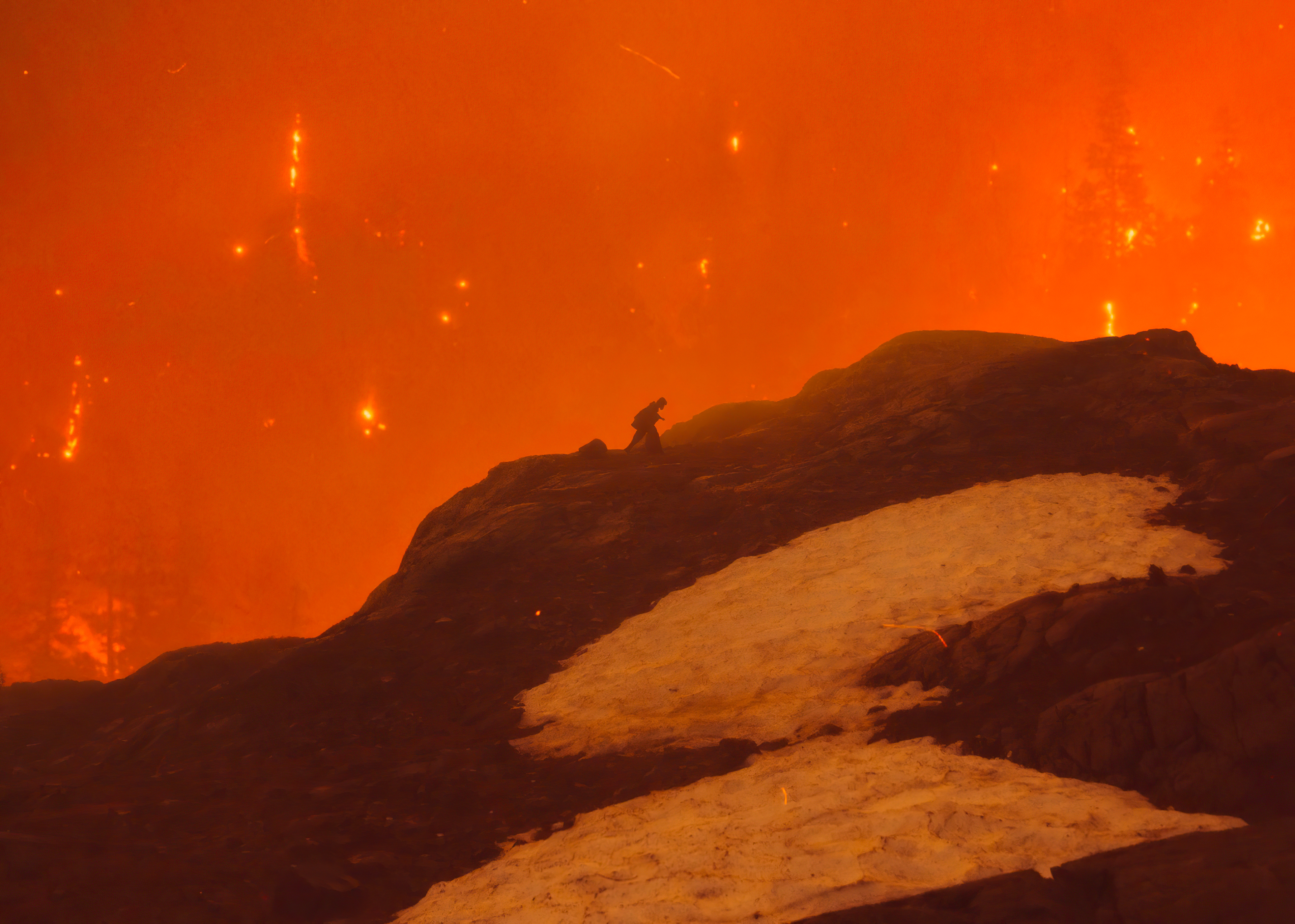 Person on a mountain during a wildfire 4K HD Wallpaper