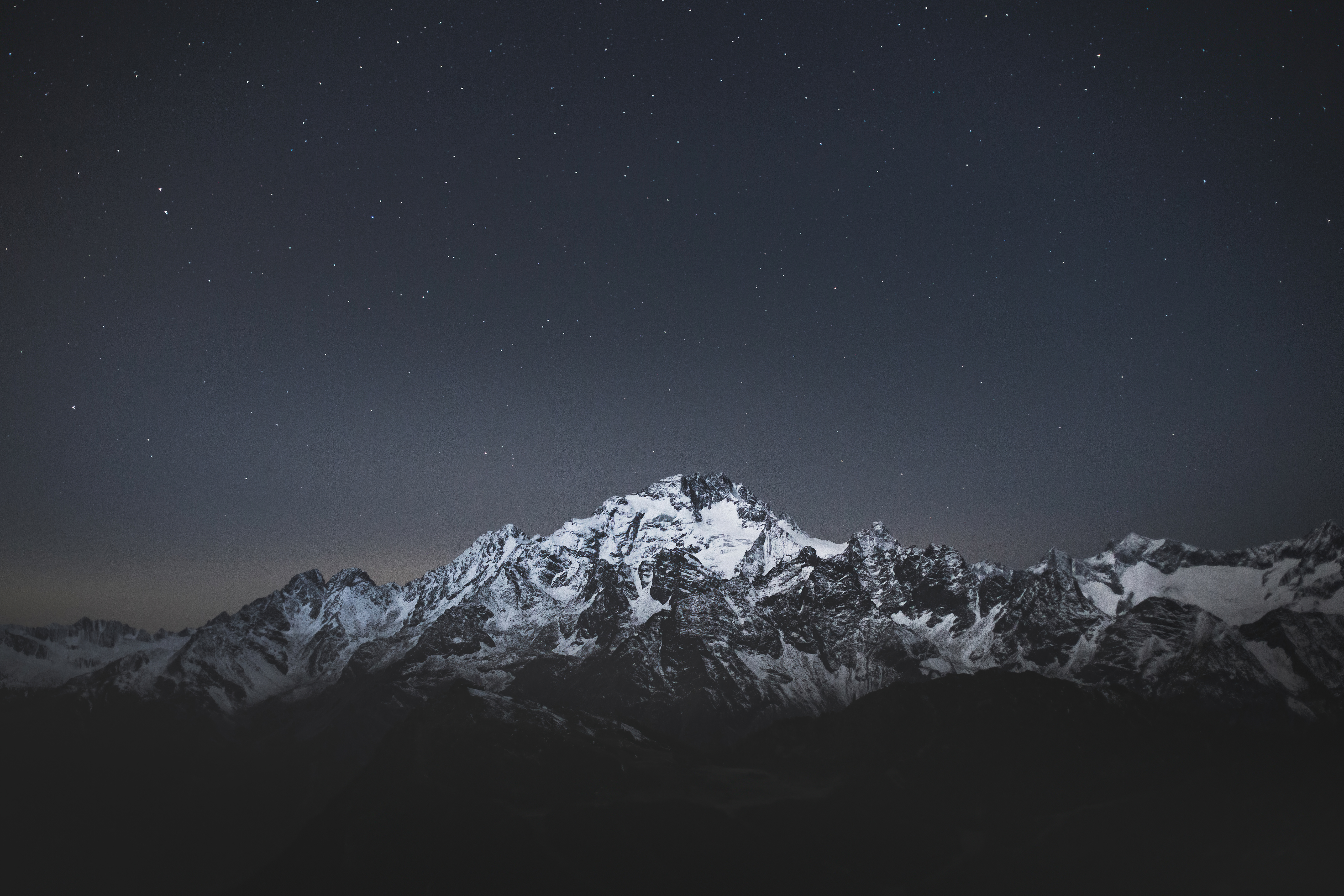 Snow-capped mountains under a starry night sky HD Wallpaper