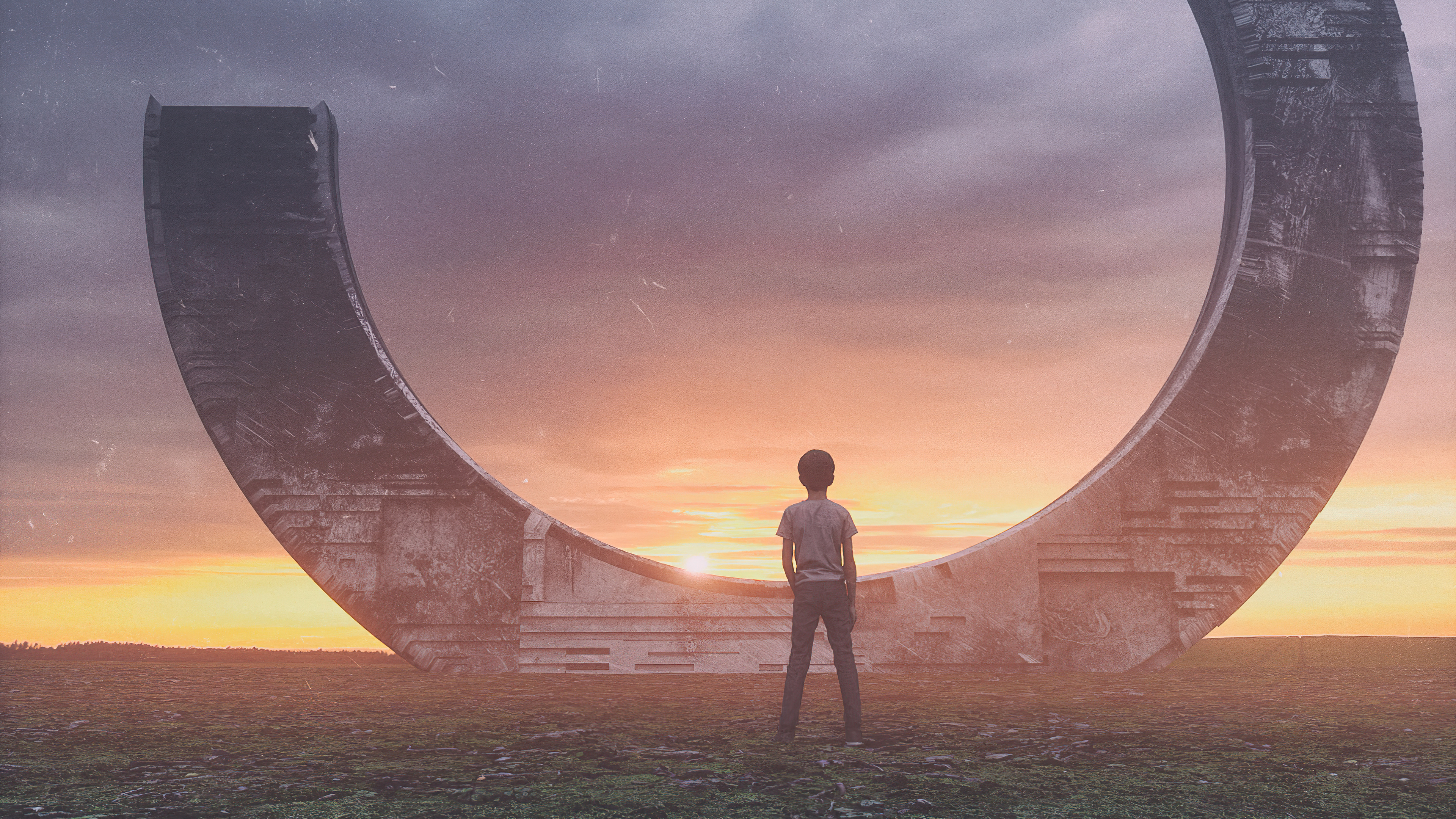 Boy standing before a large circular structure at sunset HD Wallpaper