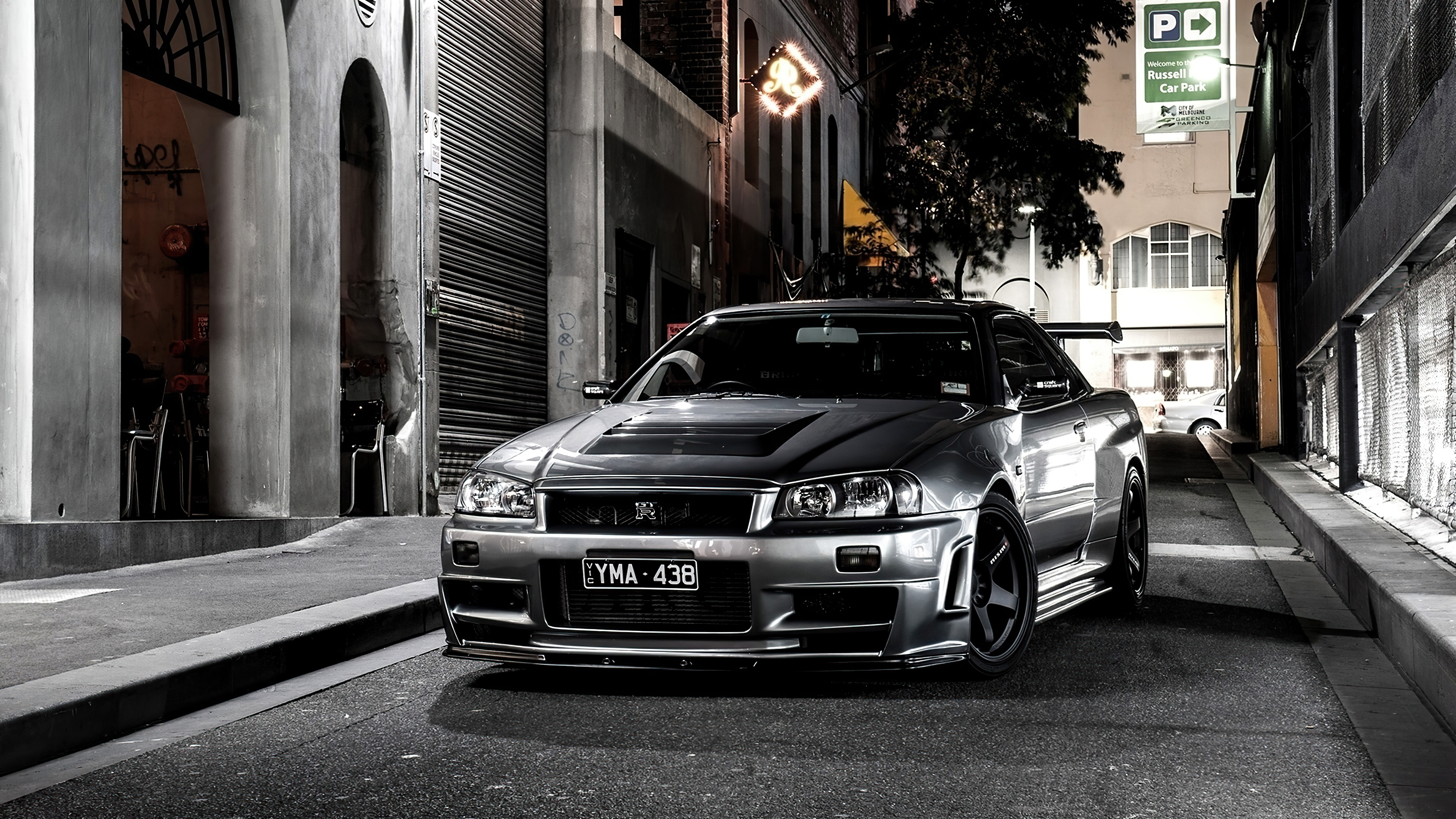 Nissan GT-R R34 parked on a city street at night HD Wallpaper
