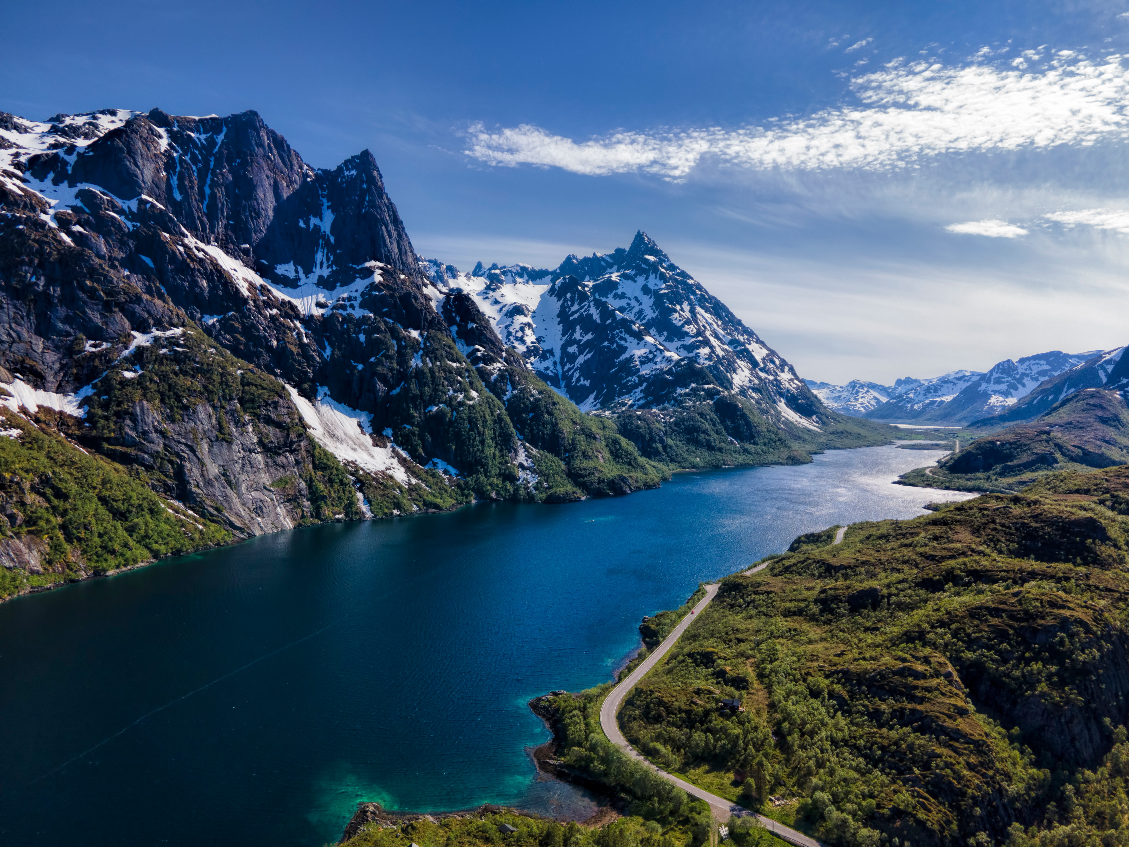 Snow-capped mountains and a lake with a road HD Wallpaper