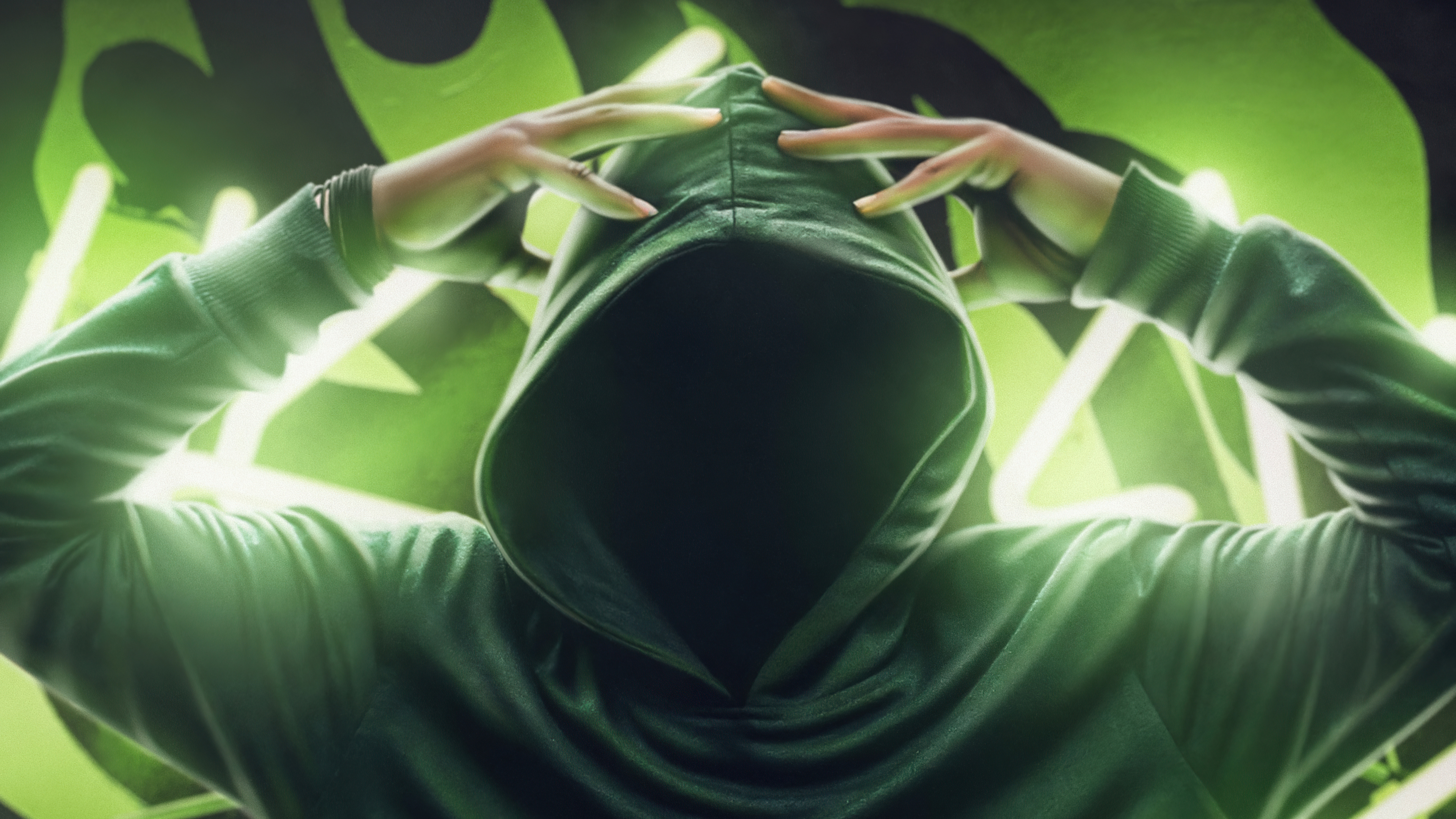 Person in a green hoodie with hands on head HD Wallpaper